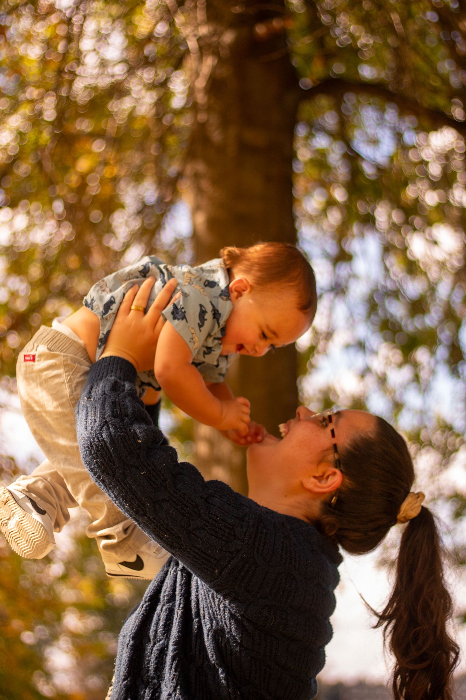 Joyful outdoor family moment captured during golden hour under trees.