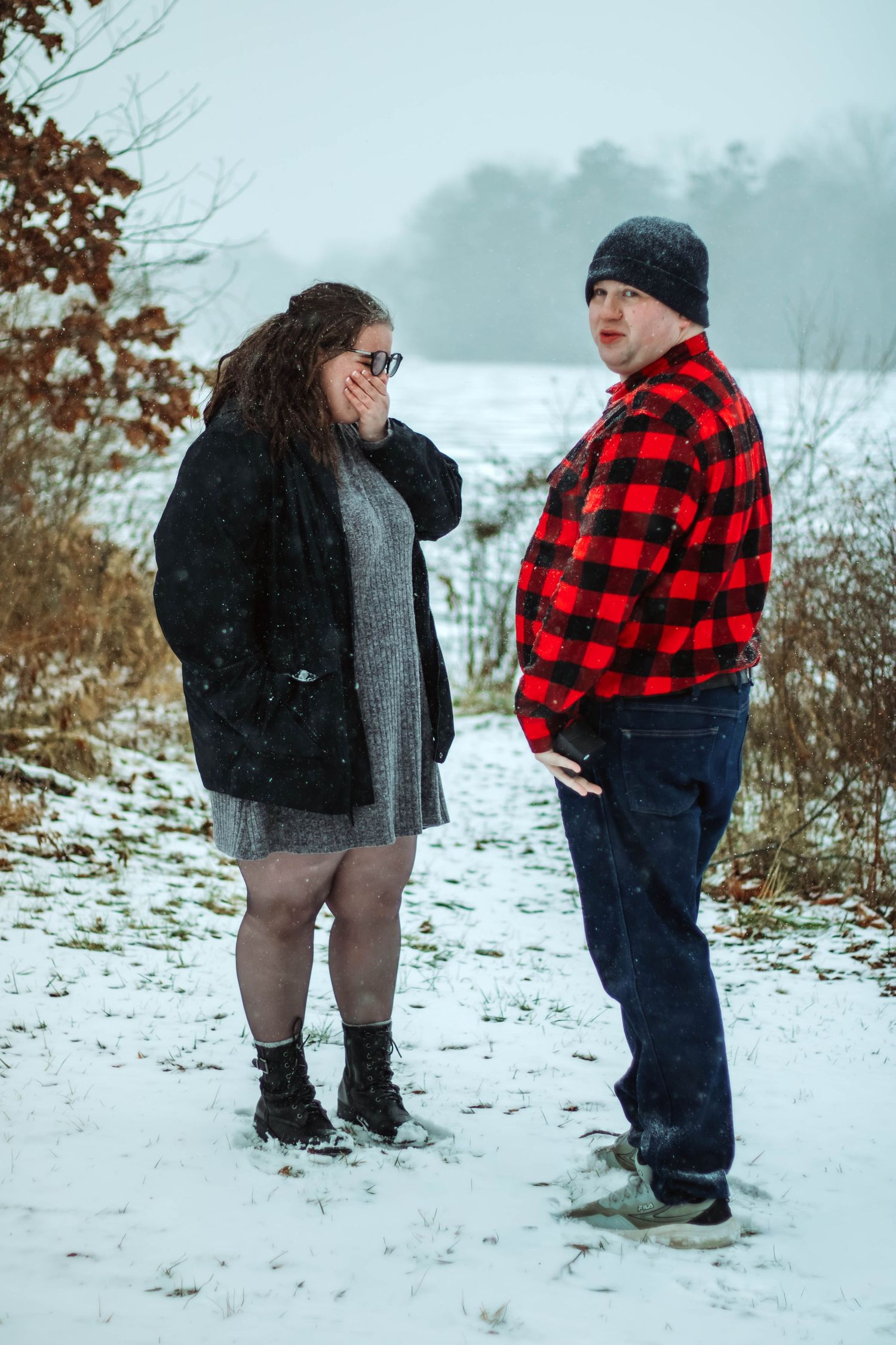 Two people having a conversation in the snow, one wearing a red plaid jacket and the other in black.