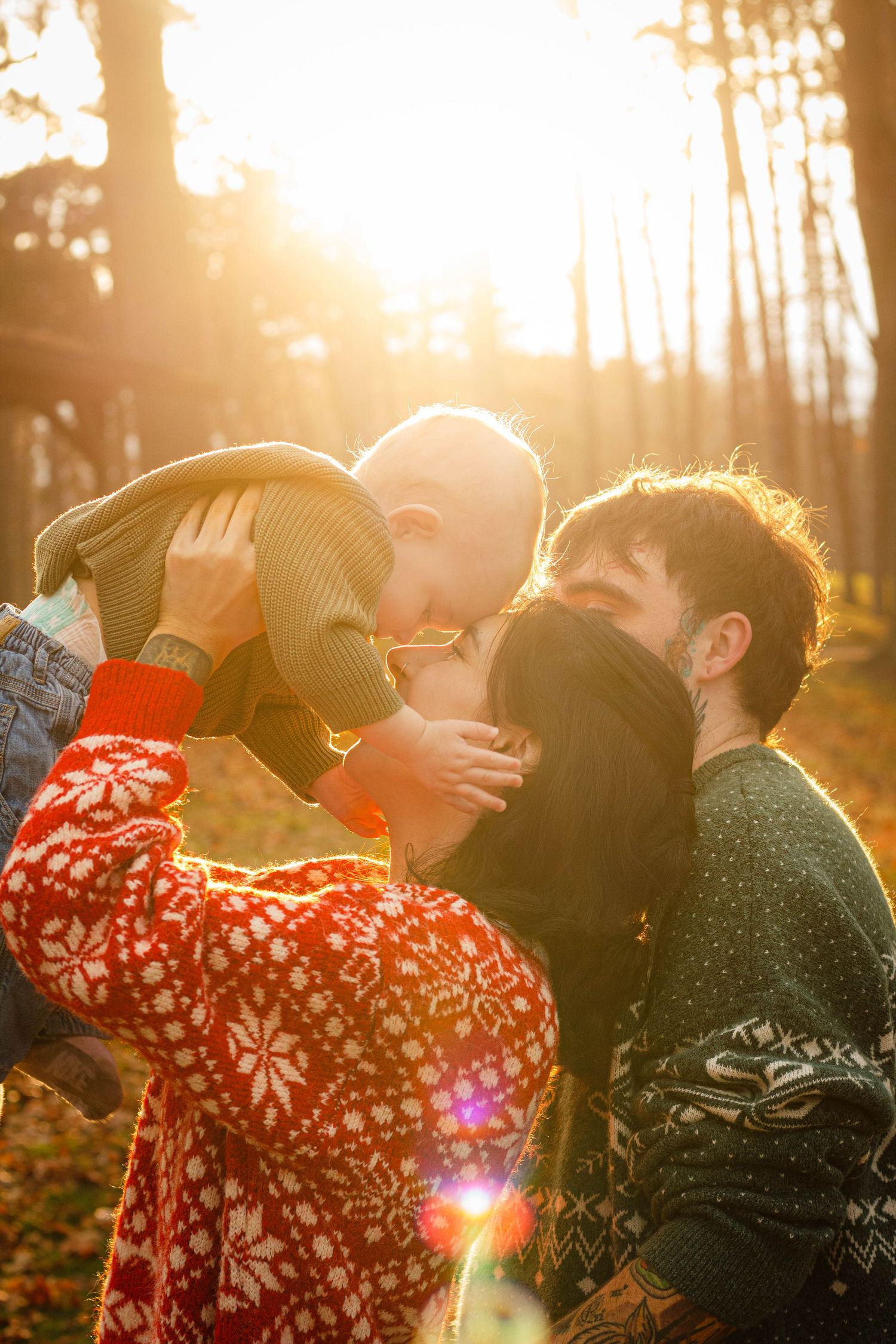 Couple in winter sweaters sharing an intimate moment at sunset in a forest setting.