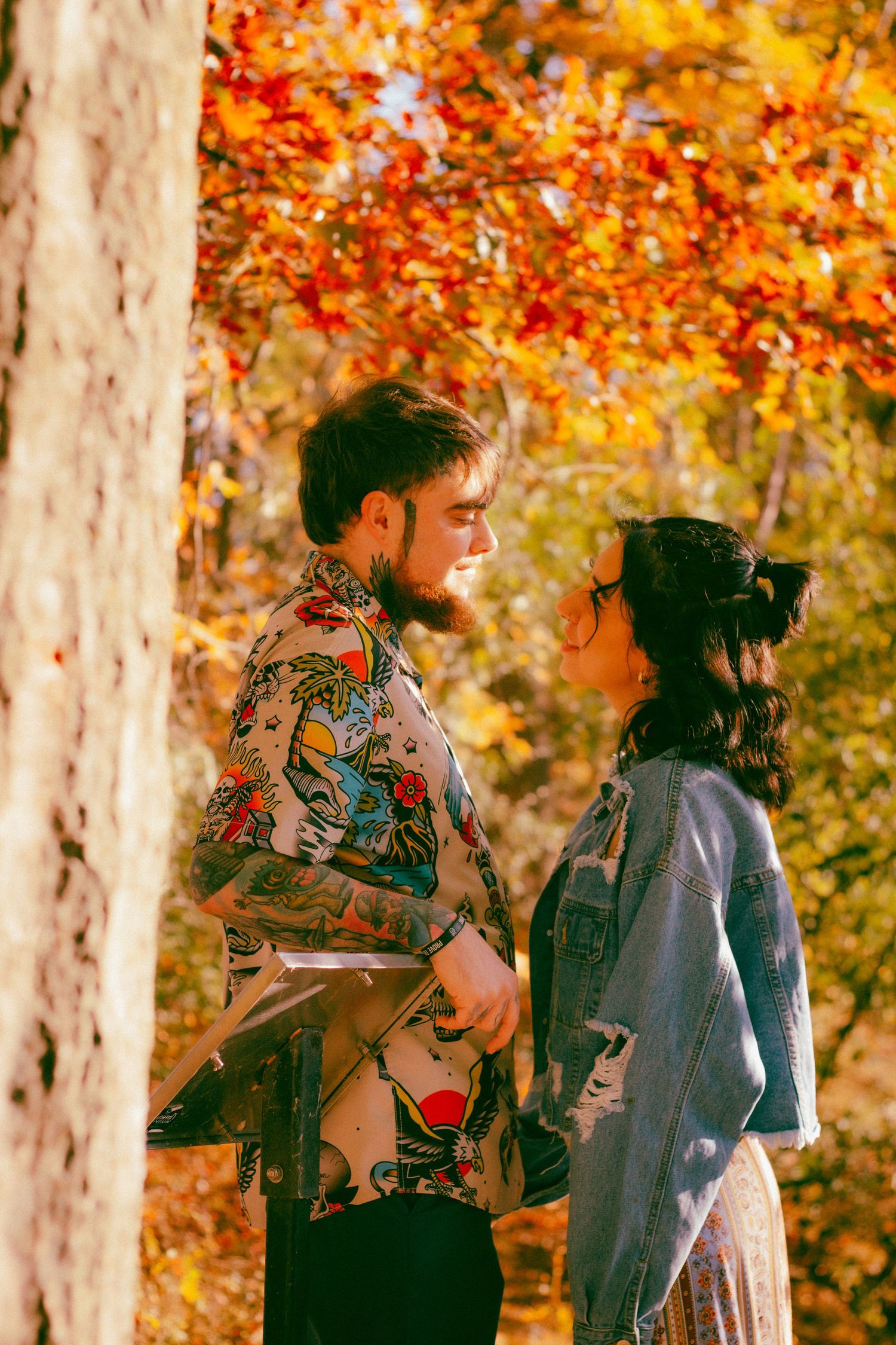 A couple shares tender moment among vibrant autumn trees with golden leaves.