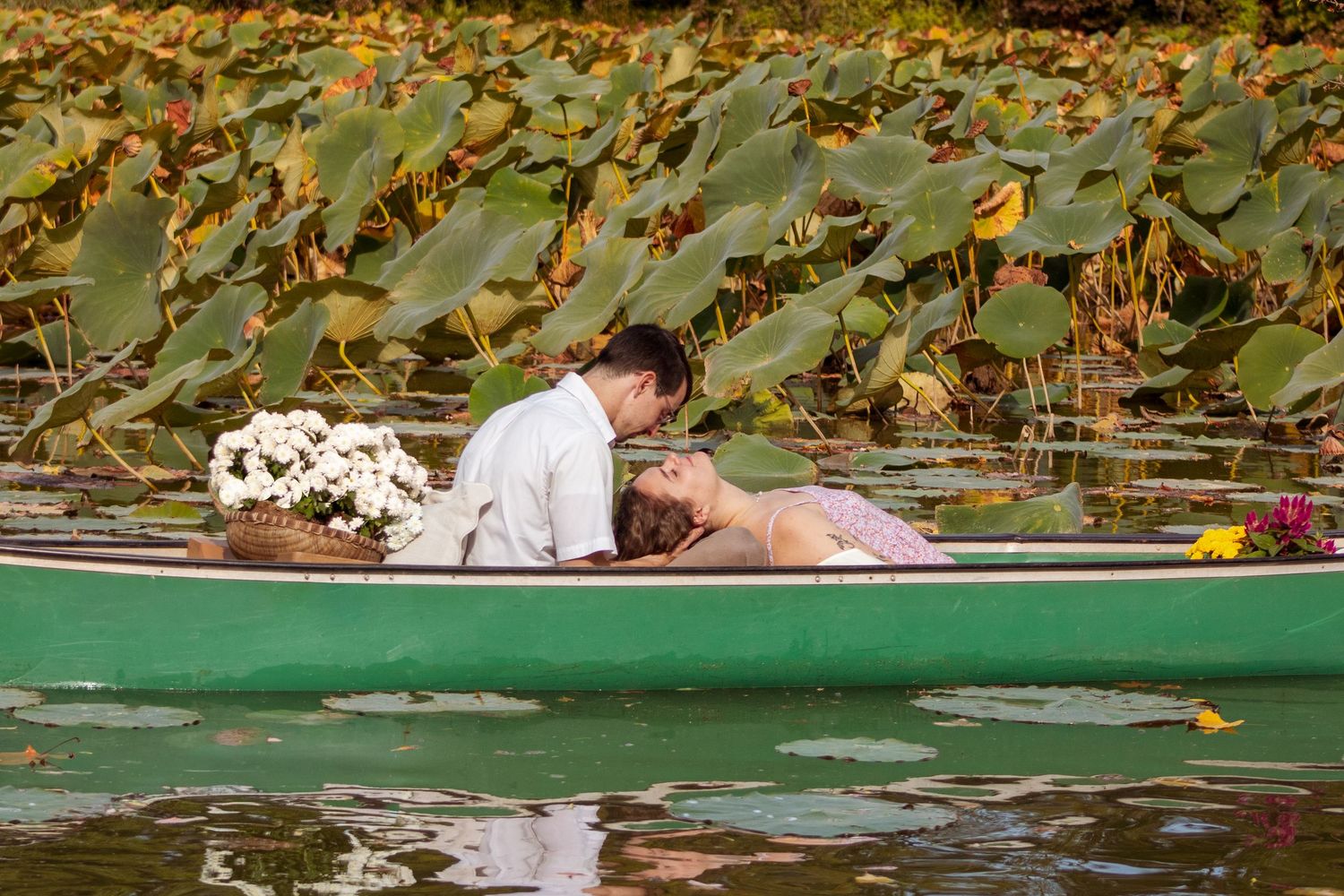 Romantic couple lying in green canoe surrounded by lily pads.