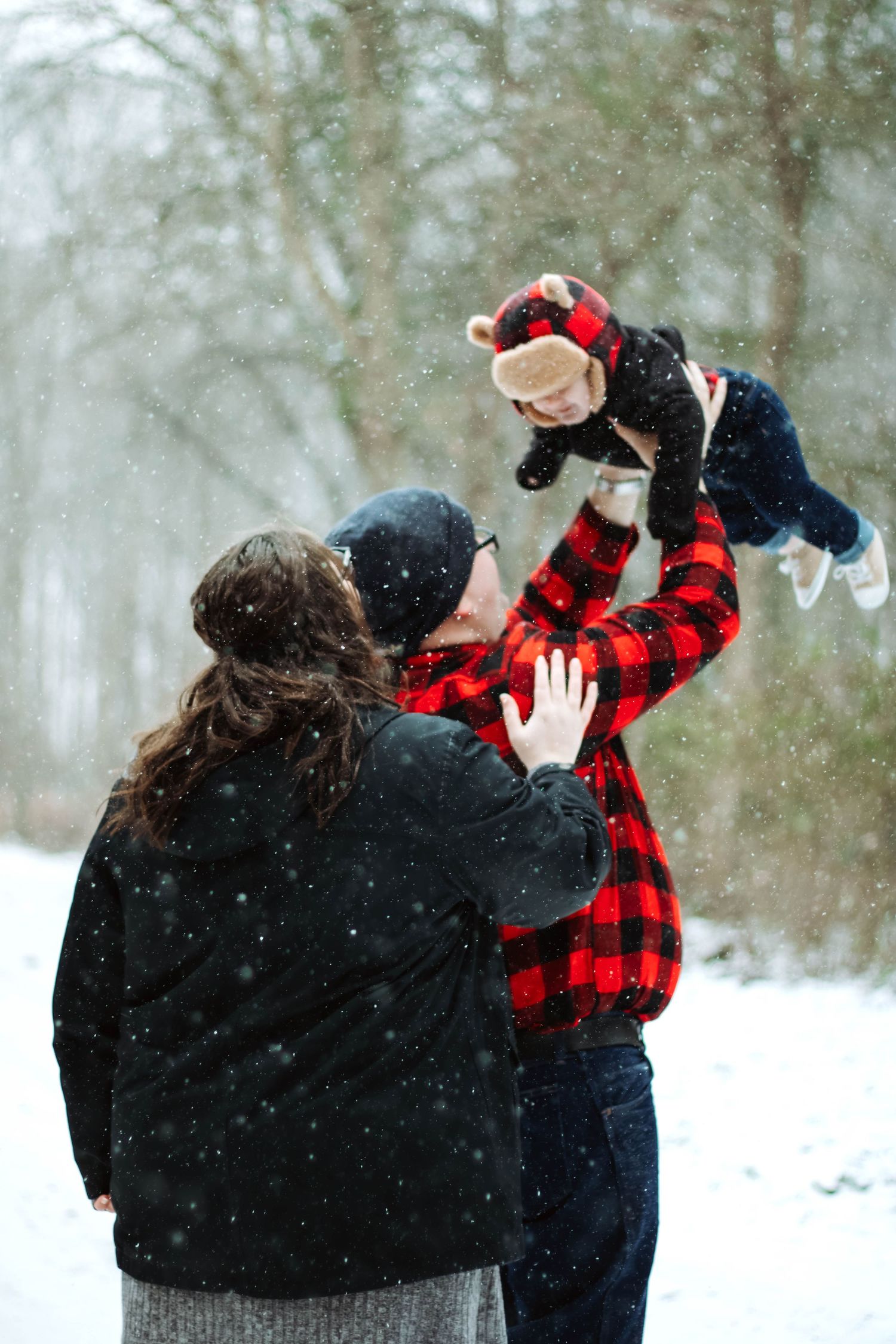 People playing in snow wearing buffalo plaid and winter gear.