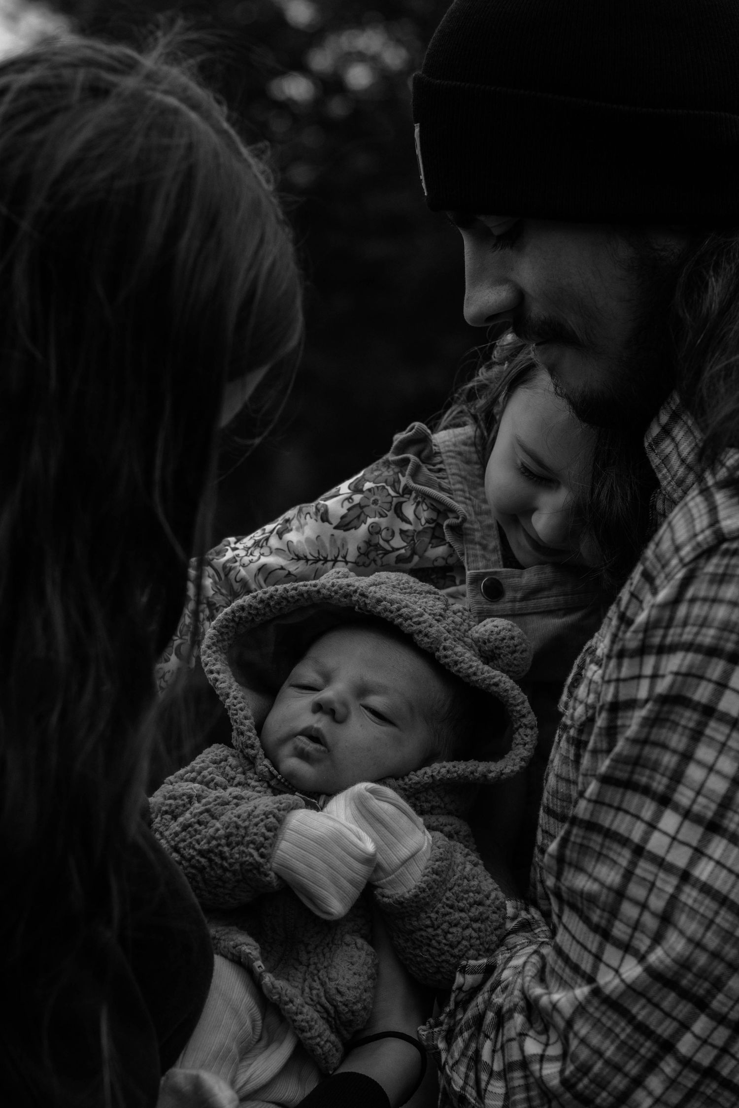 A tender black and white photograph of a sleeping baby being held in a cozy blanket.
