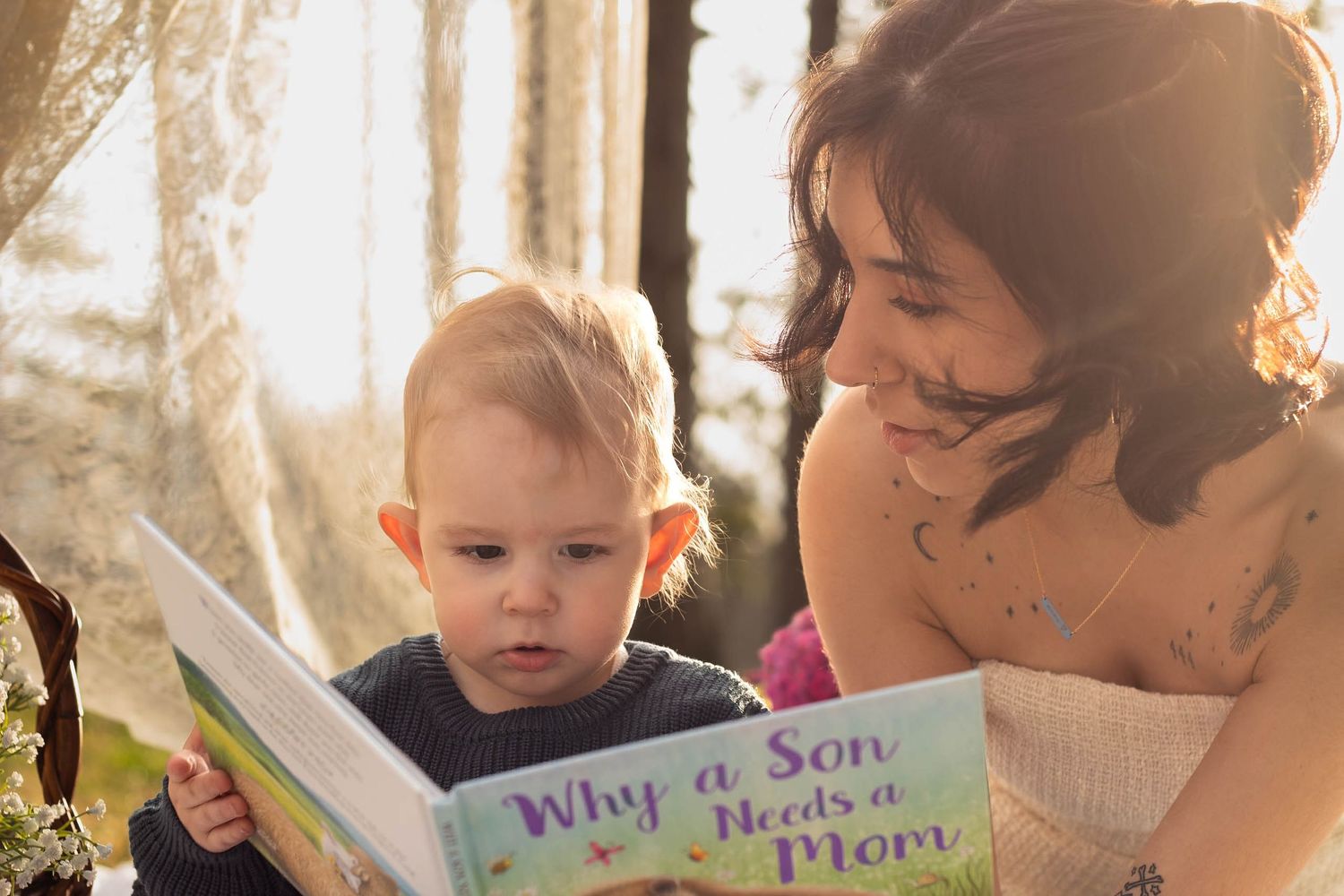 A child and adult sit together reading a colorful children's book in warm natural lighting outdoors.