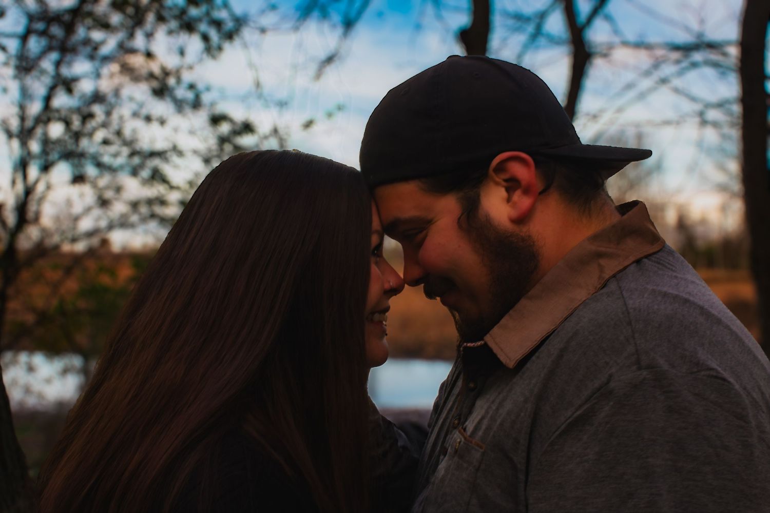 Intimate silhouette portrait of couple during golden hour with trees in background.