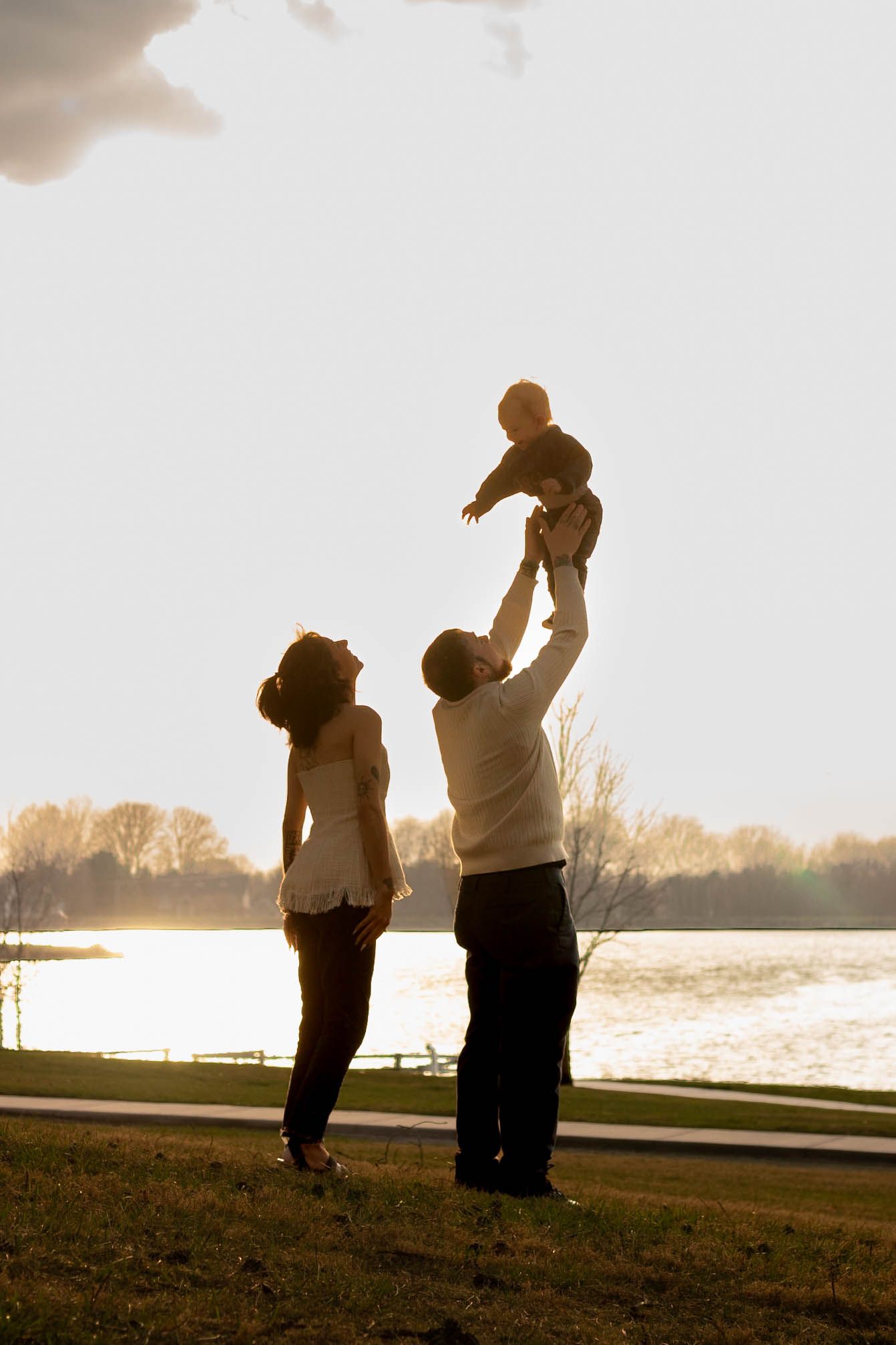 A silhouetted couple dances together at sunset by a waterfront, creating a romantic backlit scene.