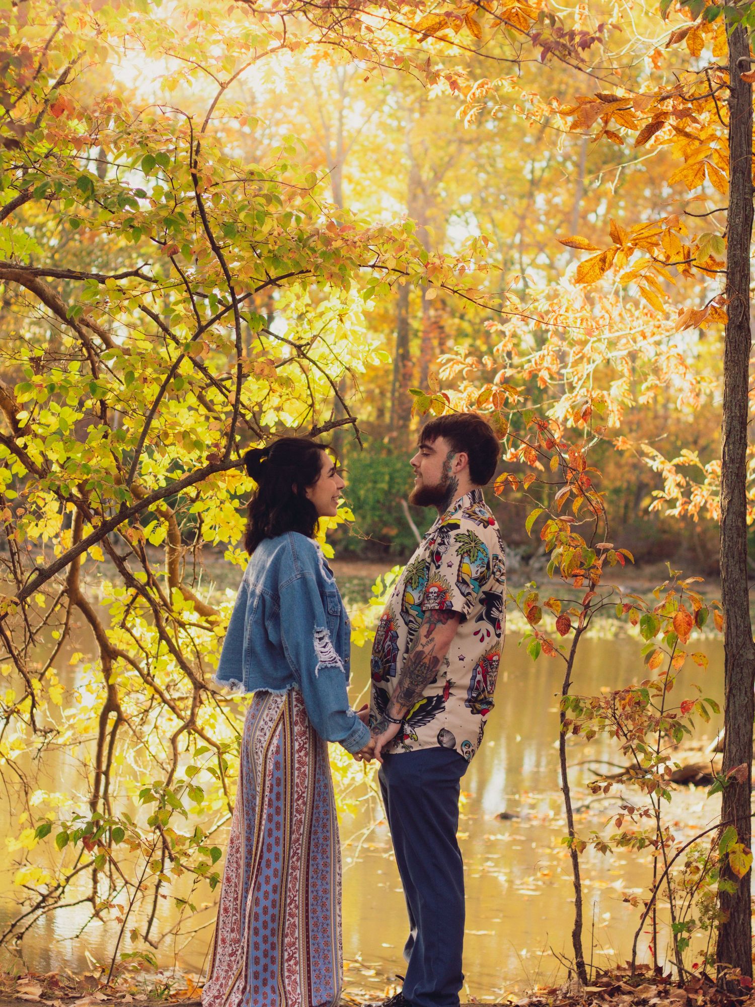 A romantic sequence captured in a park with fall foliage and a lake in the background.