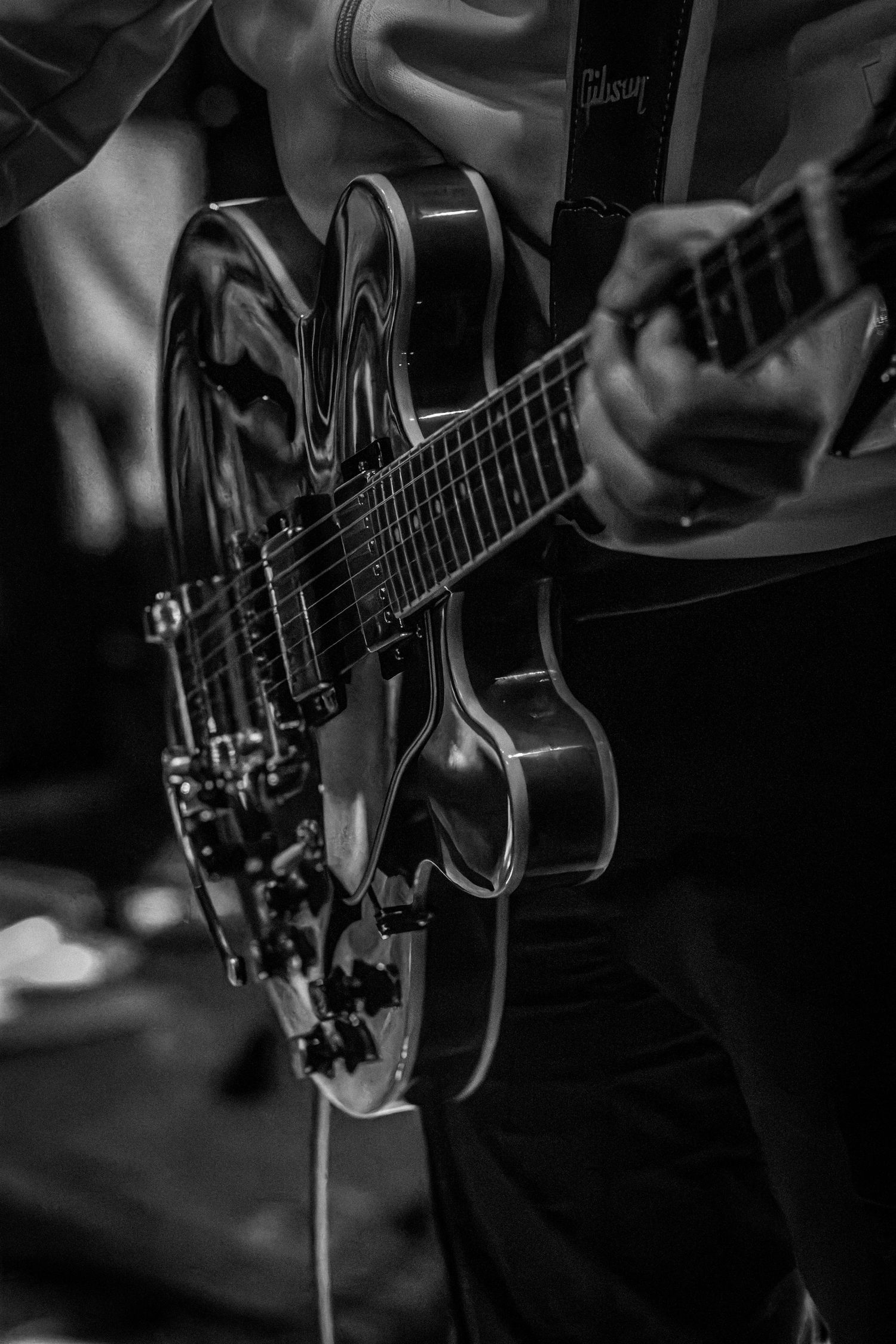 Close-up black and white shot of a Gibson electric guitar being played.