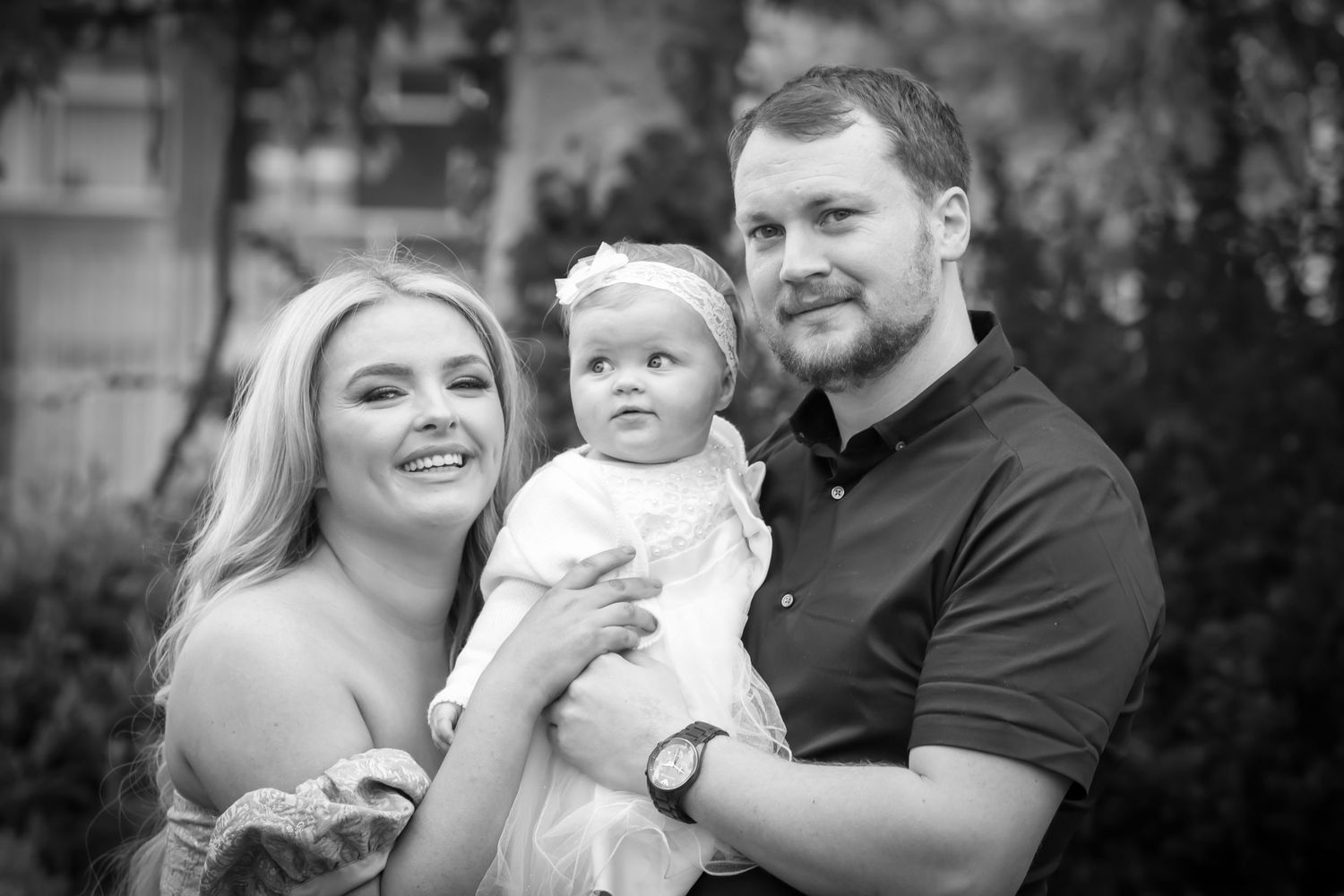 Family portrait outdoors with baby in black and white.