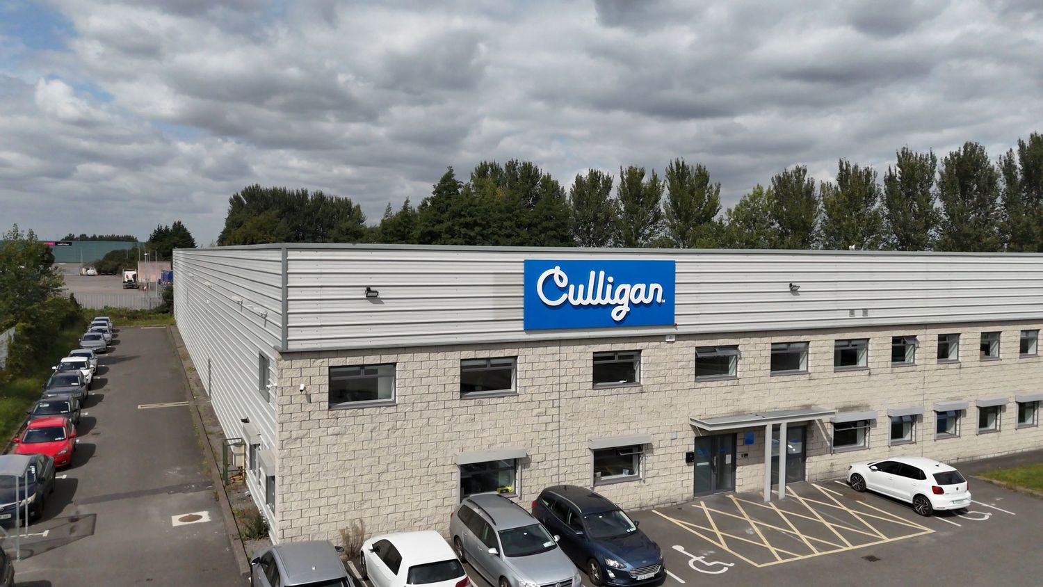 Panoramic view of a Culligan Water Solutions with Culligan store signage under cloudy skies.