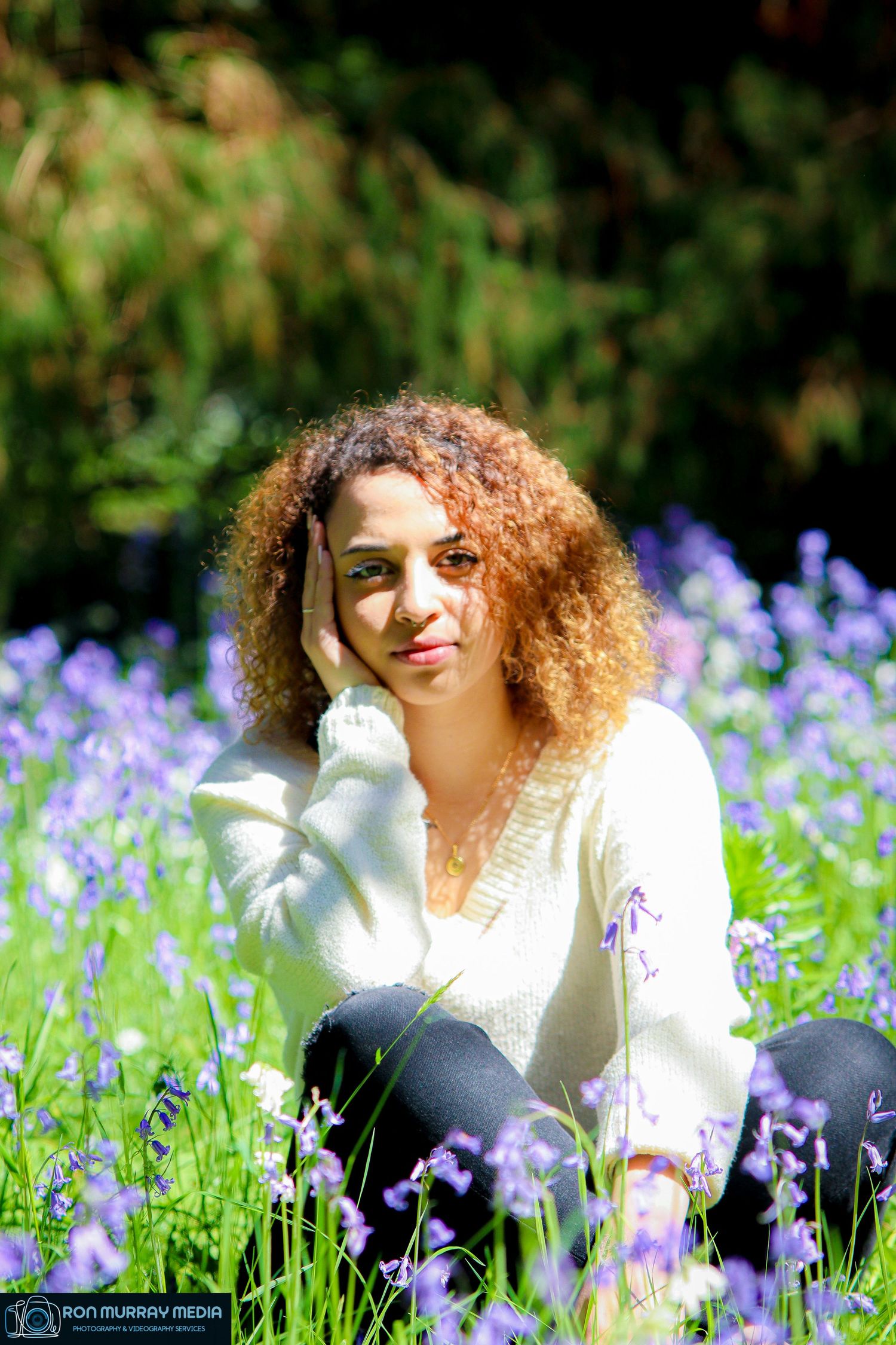 Person with curly hair lying in a field of purple wildflowers on a sunny day.