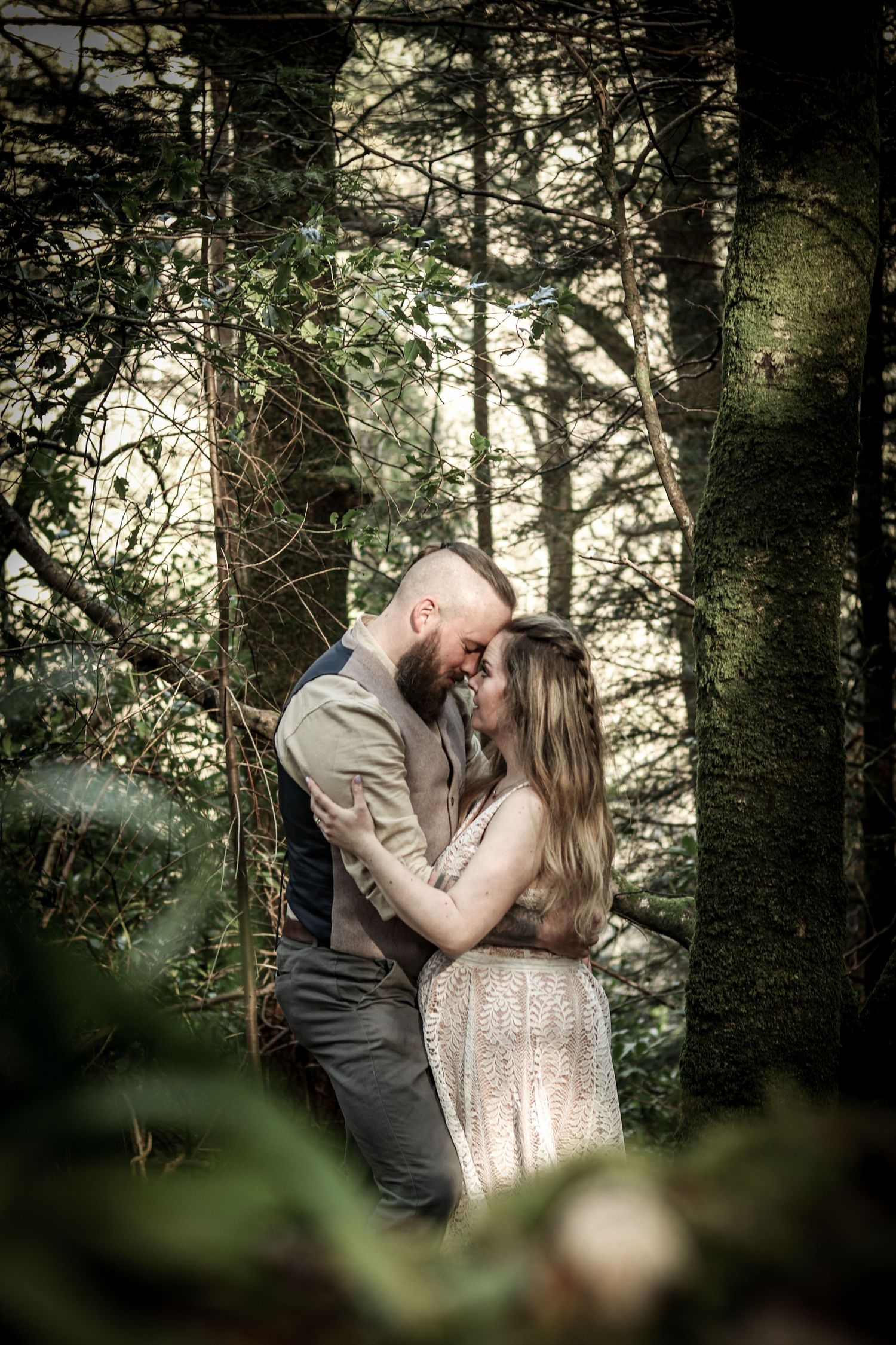 Intimate couple's photoshoot in a mystical forest setting with natural lighting.