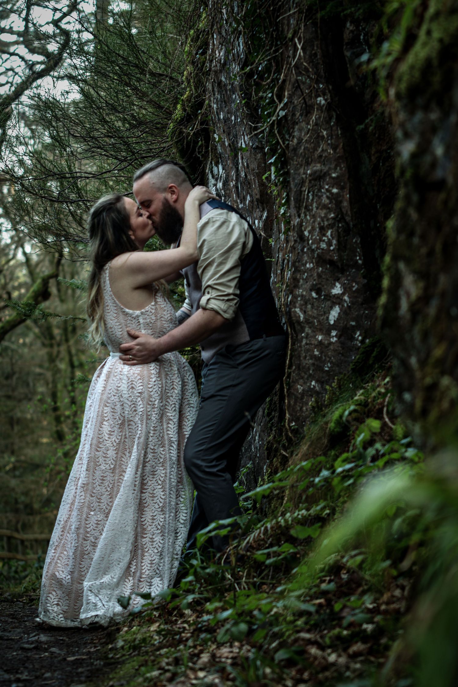 Romantic forest photoshoot with couple embracing among mossy trees.