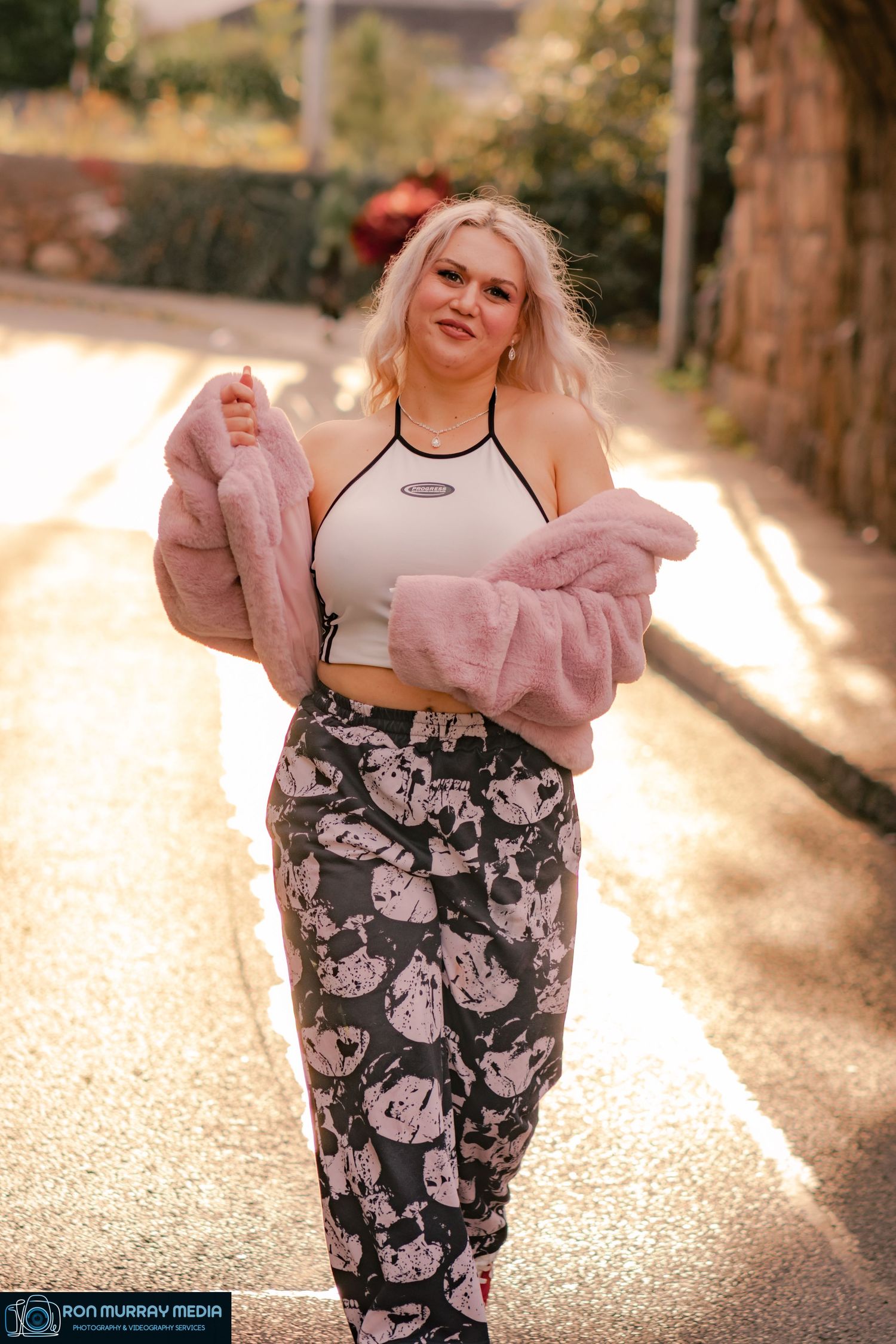 Person in floral print outfit posing on a sunlit path outdoors.