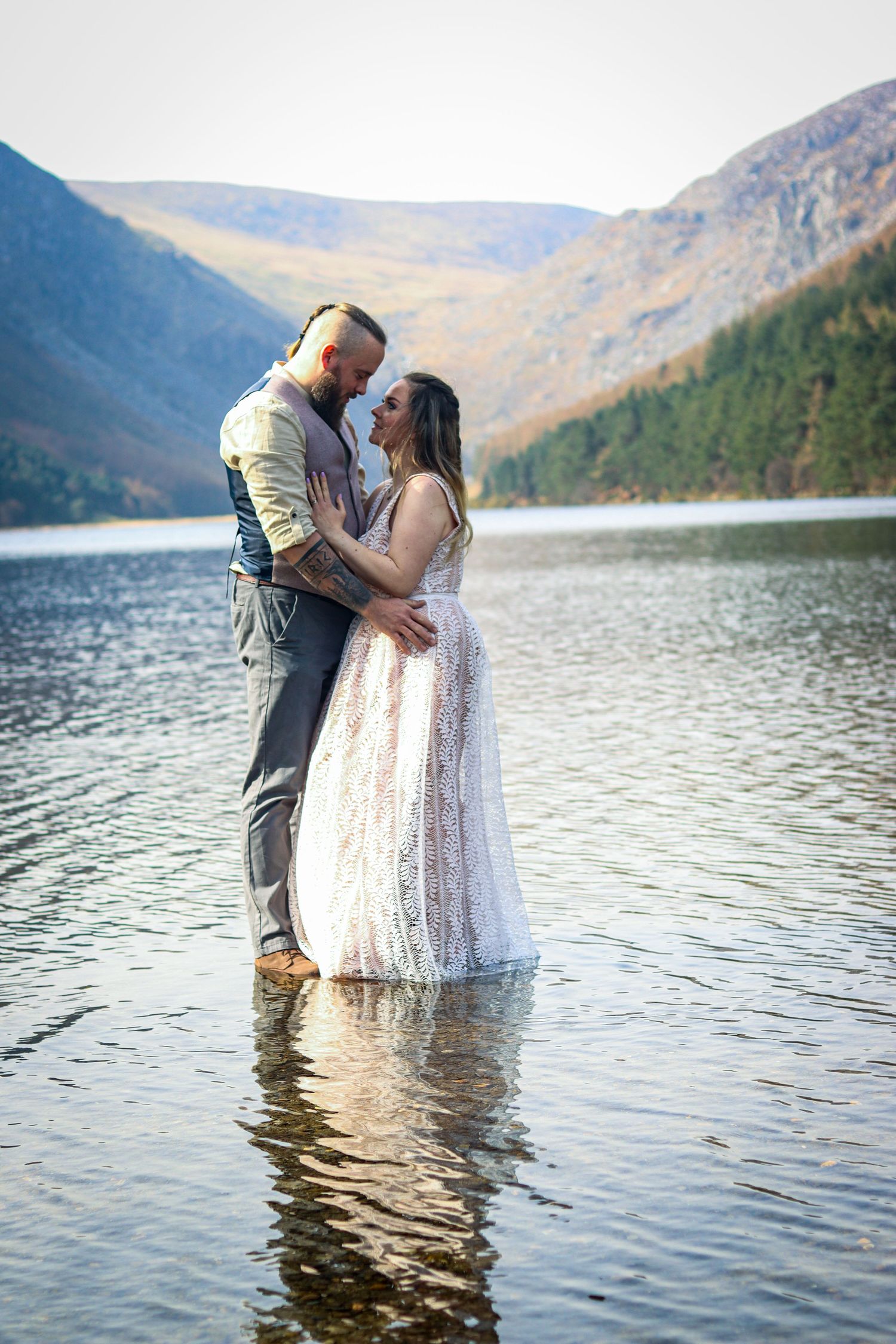 A romantic couple shares an intimate moment while standing in a scenic mountain lake.