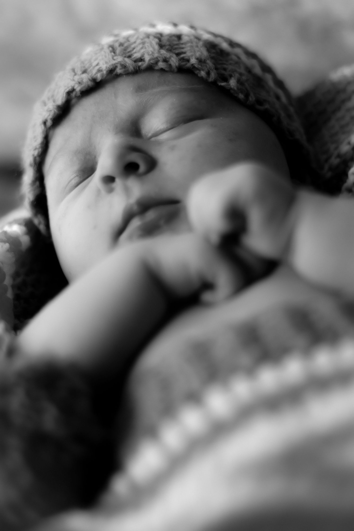 Close-up black and white portrait showing peaceful sleeping newborn.
