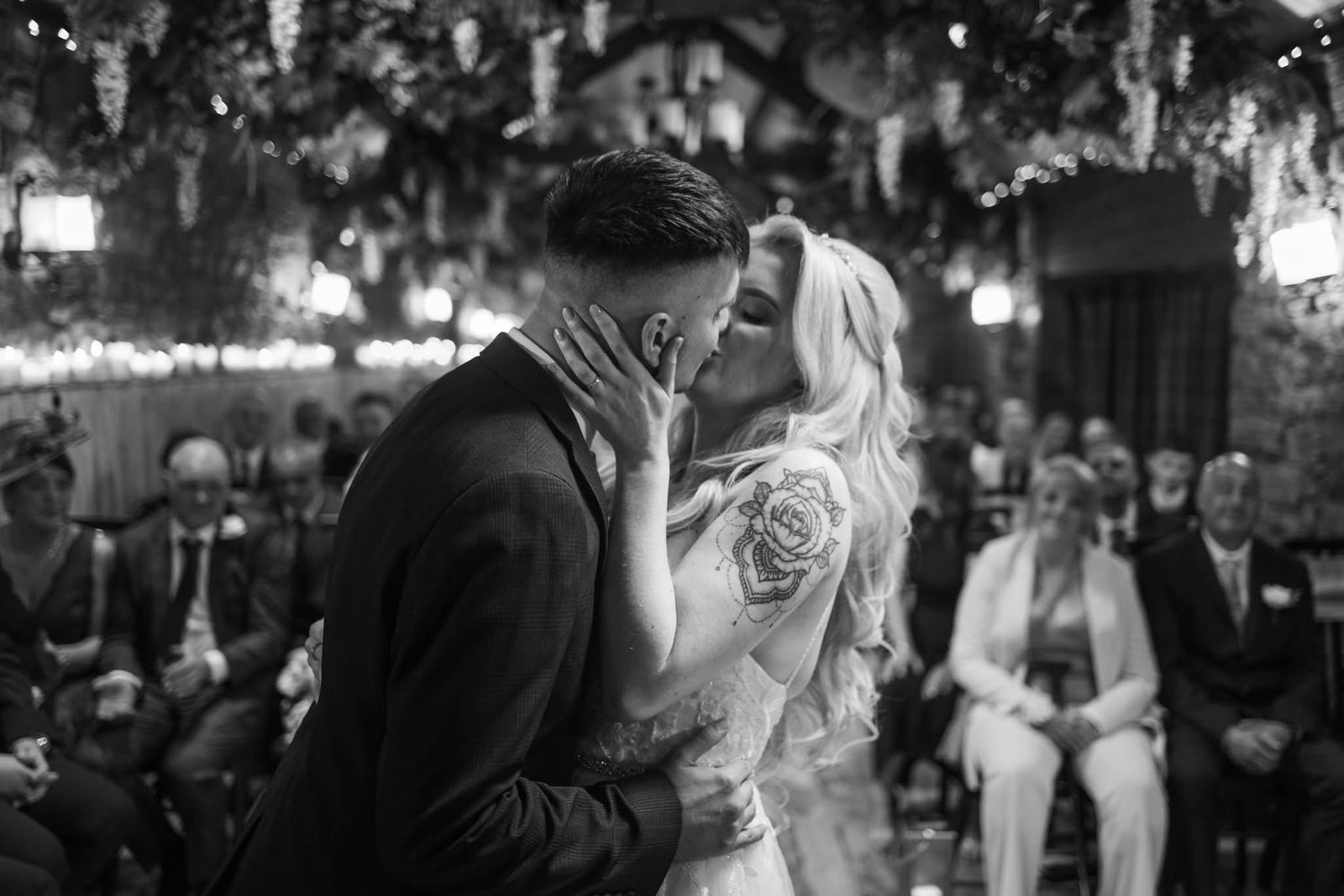 Wedding guests dance and celebrate at an outdoor evening reception under string lights.