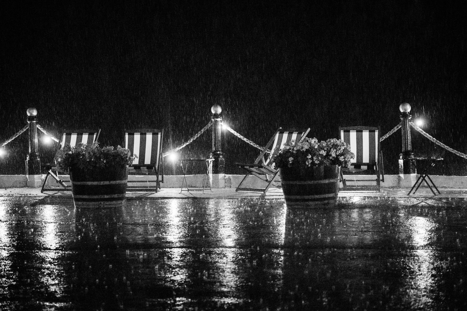 Illuminated carnival rides and attractions reflect off rippling water at night creating a magical mirrored scene.