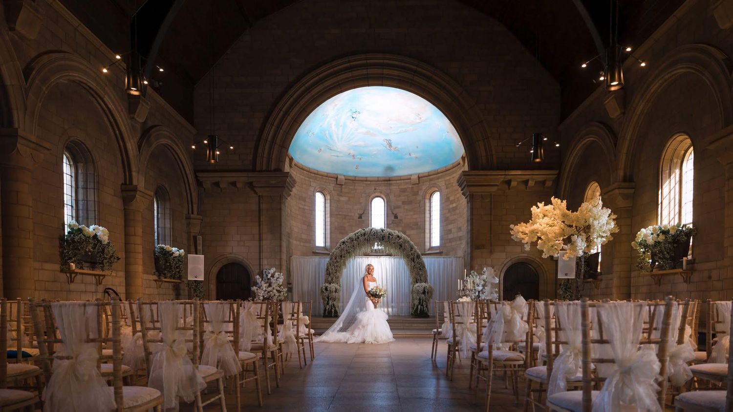 Elegant church interior with arched ceilings and chandeliers set up for a wedding ceremony.