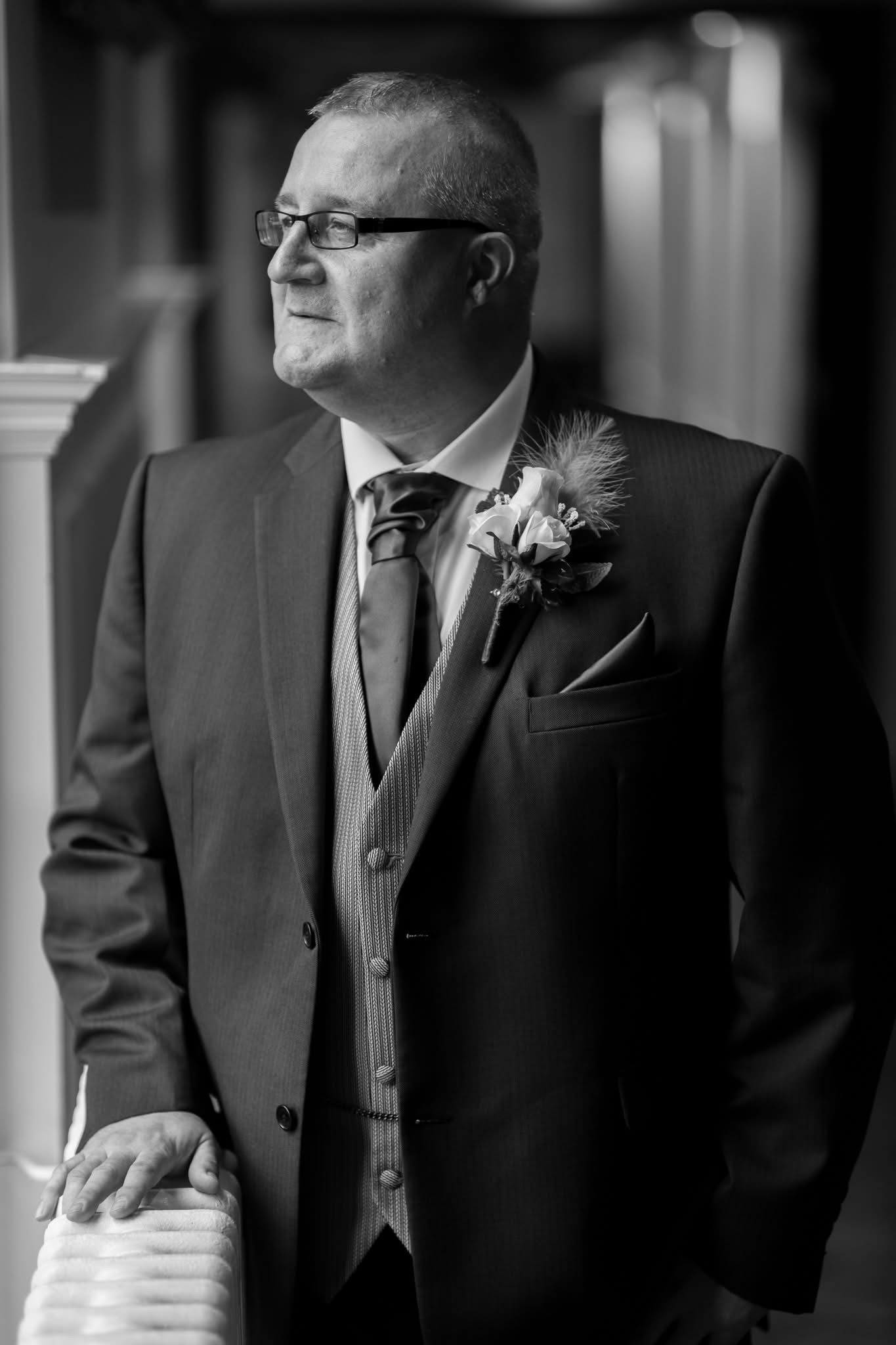Groomsmen in formal black suits and vests stand together before the wedding ceremony.