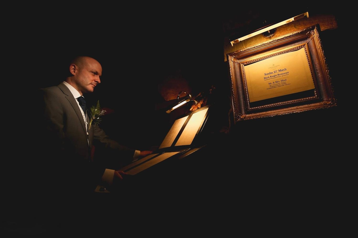A pianist performs at a grand piano in dramatic low-key lighting on a darkened stage.
