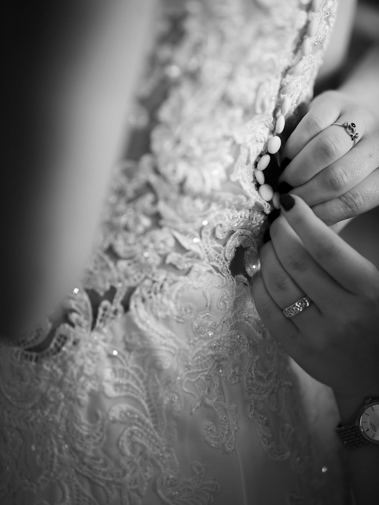 Close-up detail shot of intricate lace pattern on wedding dress in black and white.