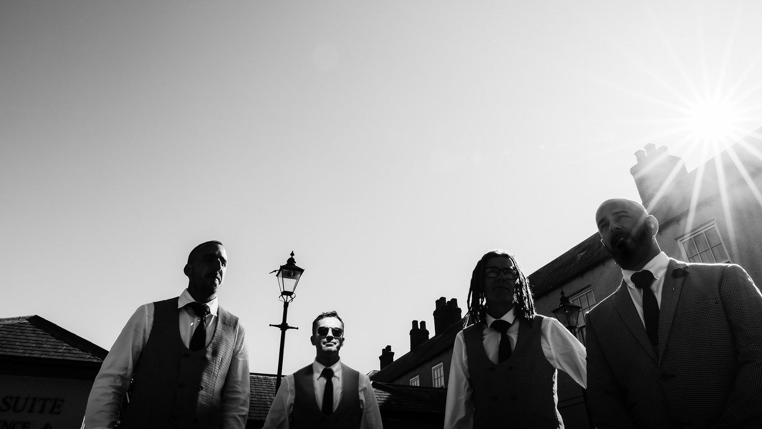 Artistic silhouette of wedding party against bright sunlight and urban architecture.