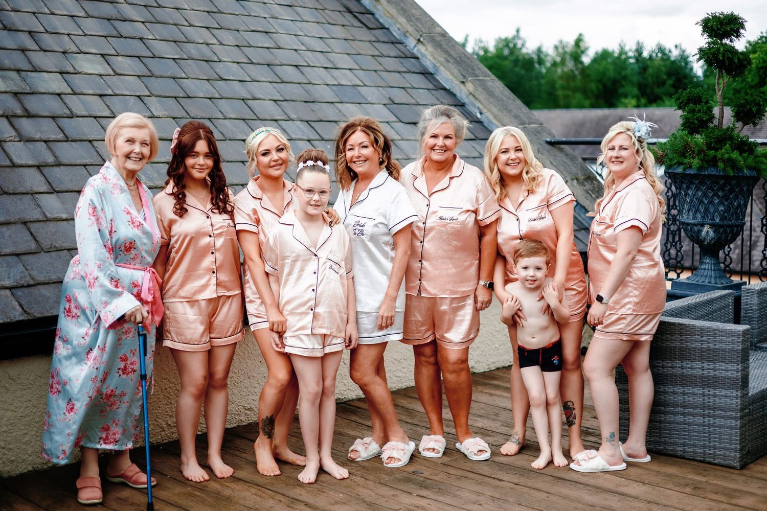 A group wearing matching pink satin robes poses together for a celebratory photo shoot.