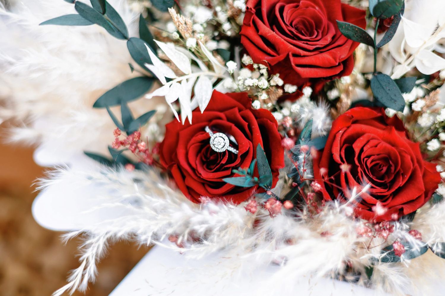 Red roses and white flowers create an elegant winter wedding bouquet with evergreen accents and sparkling details.