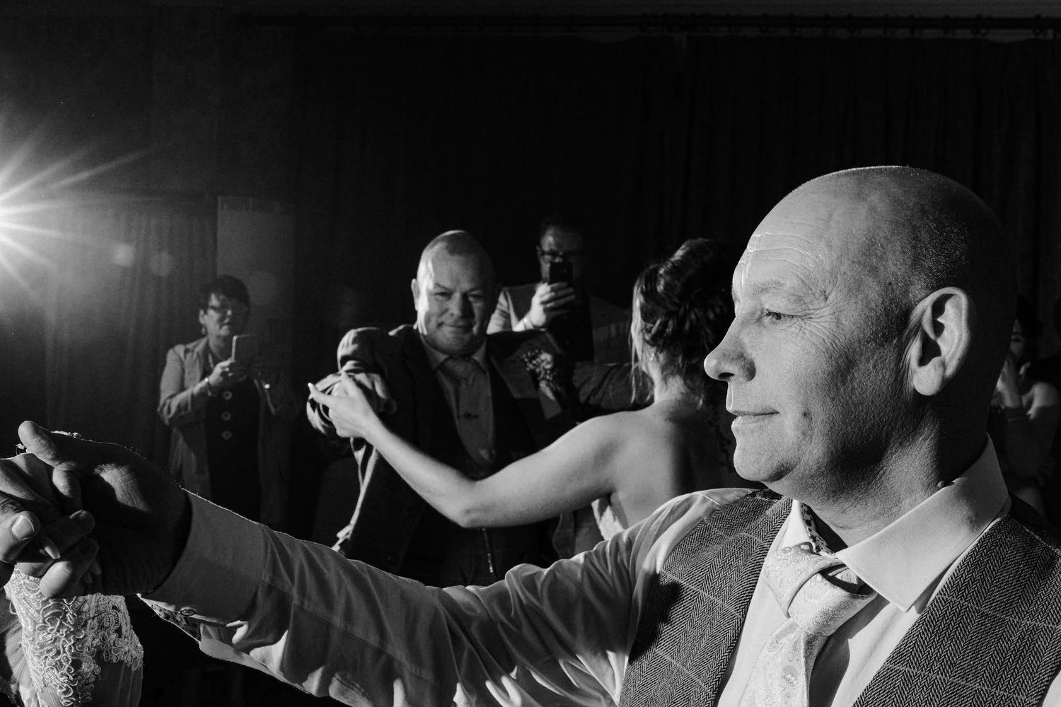 Black and white candid wedding reception photos showing guests dancing and celebrating.