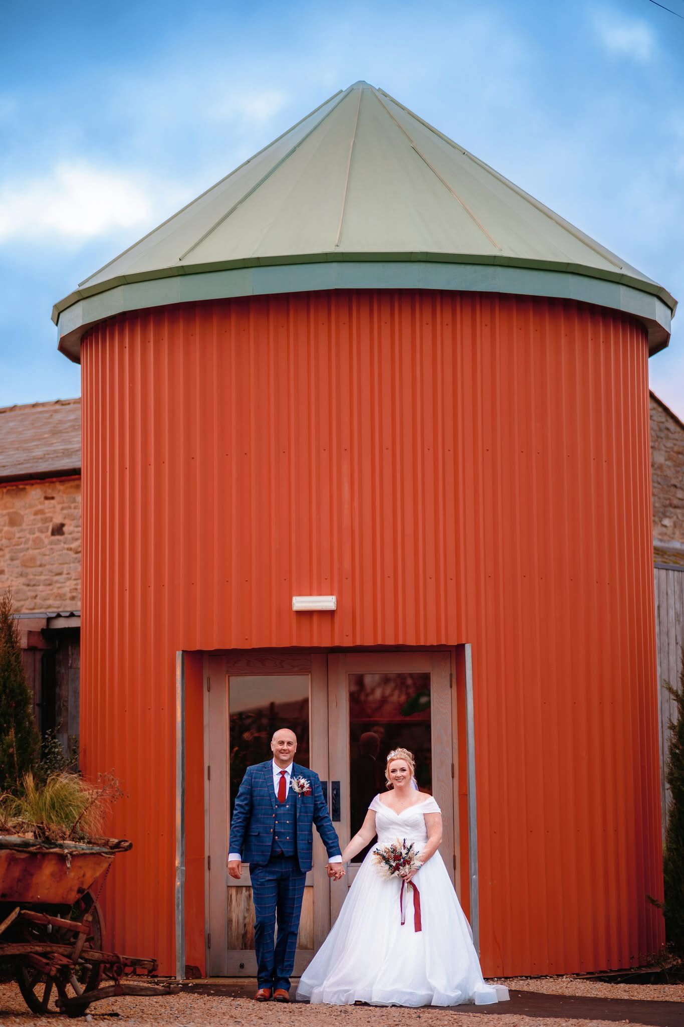 A series of wedding photos showing a couple posing in front of a rustic red barn structure with curved roof architecture.