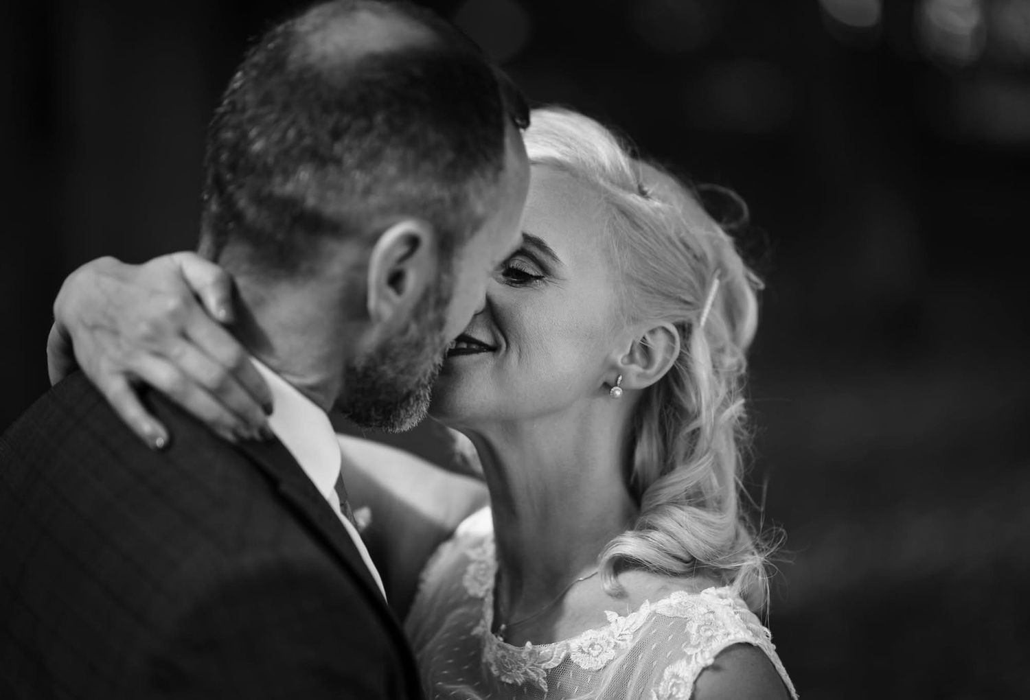 A romantic black and white wedding kiss moment captured during an outdoor ceremony.