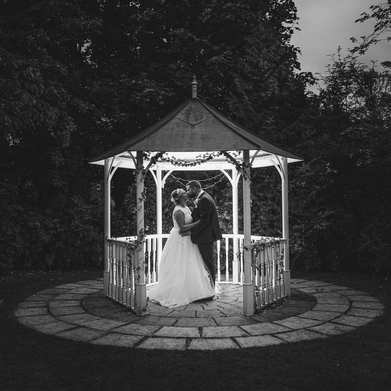 A series of black and white wedding photos showing a gazebo and couple in various romantic poses at an outdoor venue.