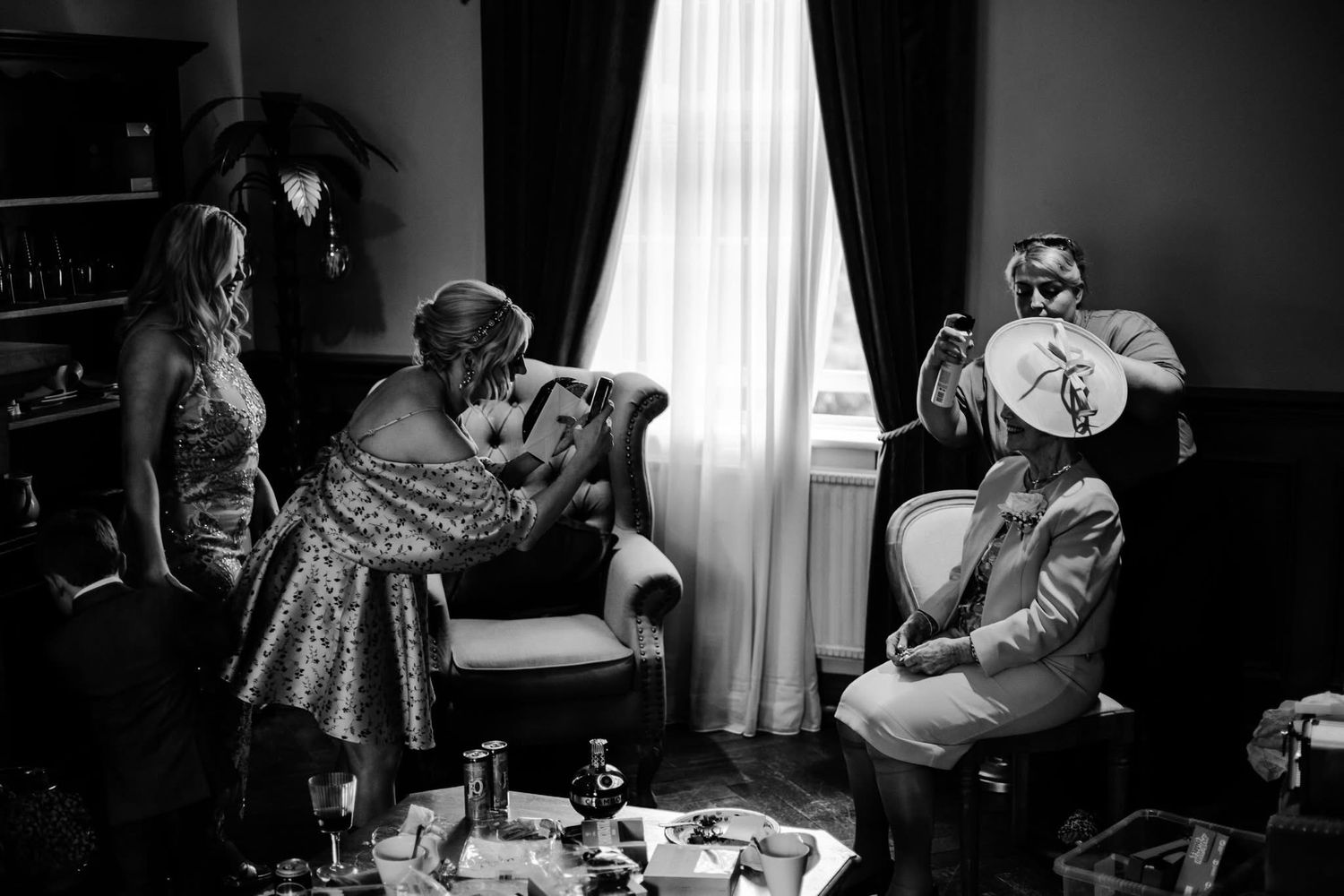 A series of black and white photographs showing a figure sitting at a table in a room with window light.