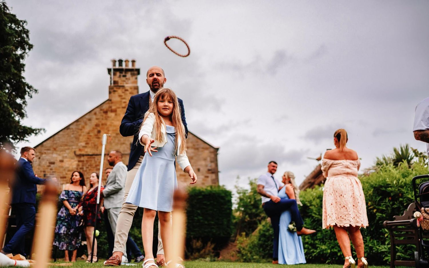 Wedding guests play lawn games during an outdoor garden reception.
