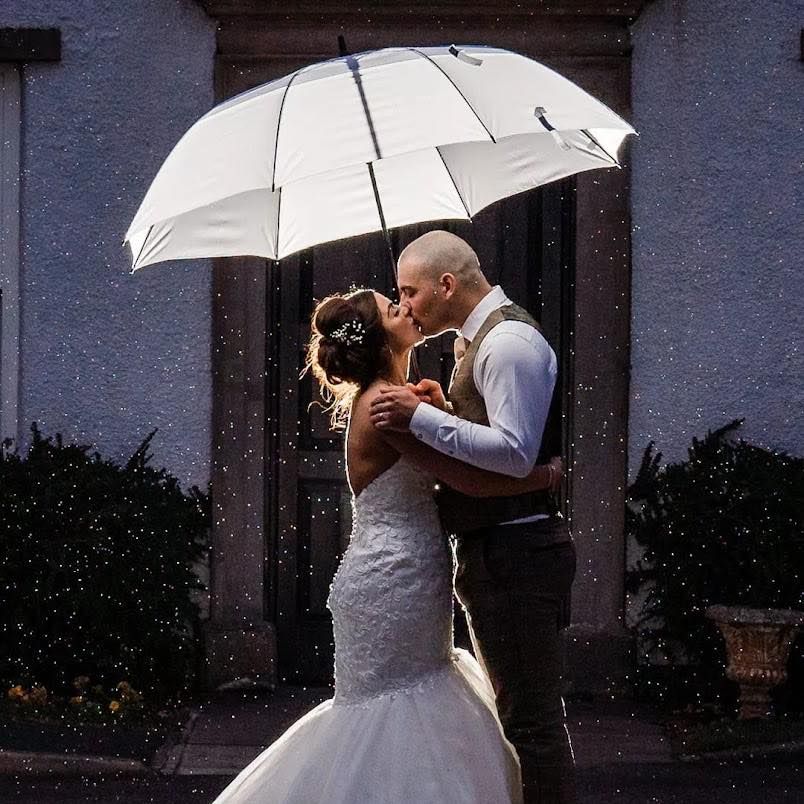 A romantic moment under a white umbrella as newlyweds share an intimate embrace.