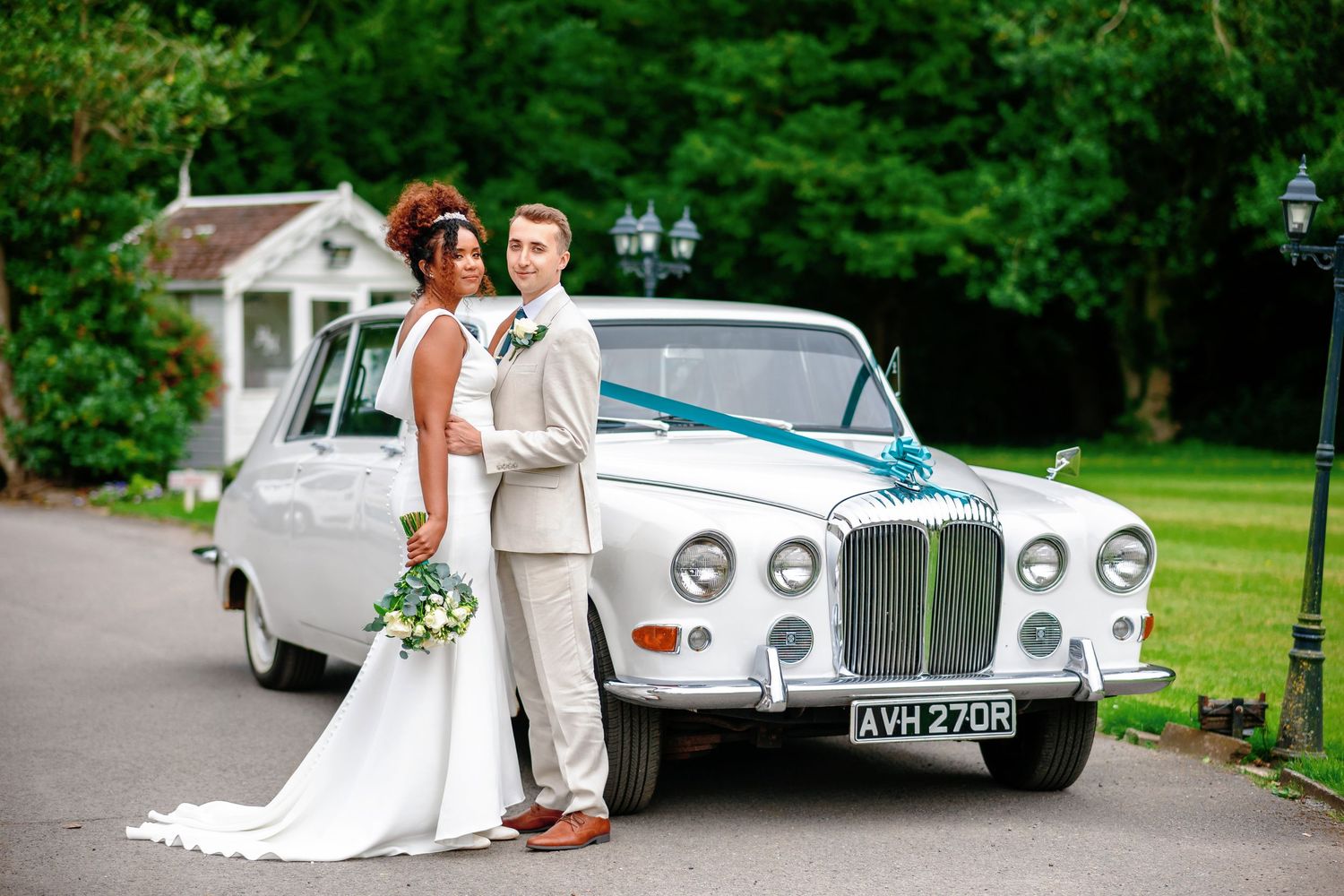 Vintage Rolls-Royce luxury car parked on lush green grounds during an elegant outdoor wedding celebration.