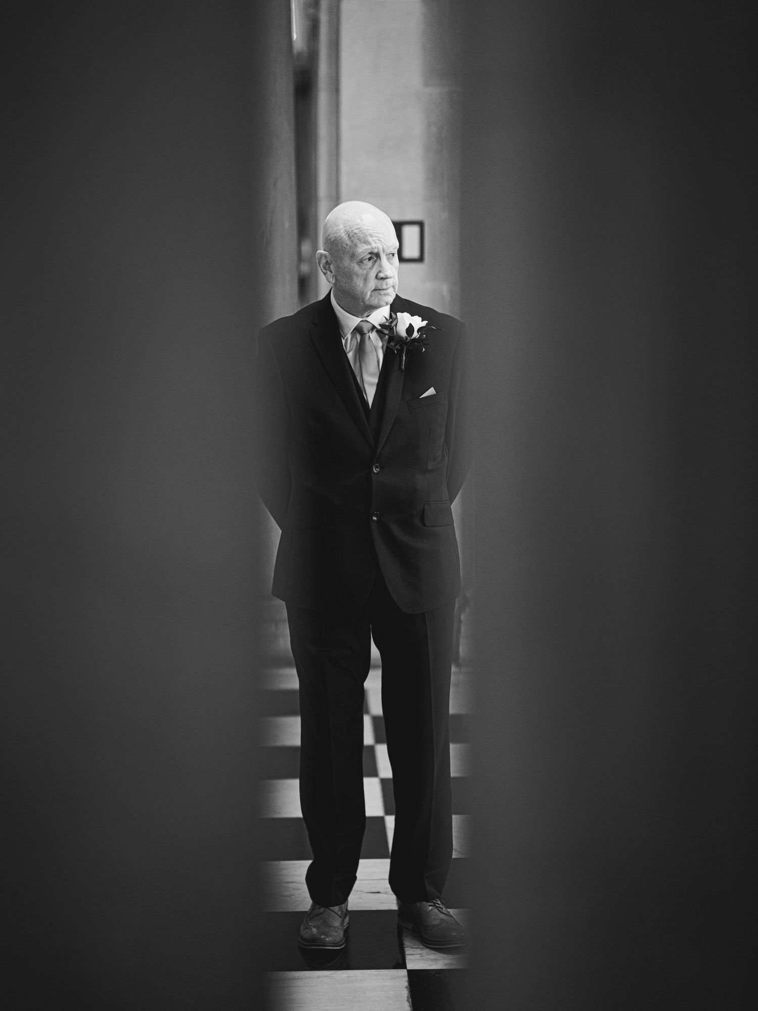 A dramatic black and white photograph shows a figure standing in a dark corridor with dramatic lighting and shadows.