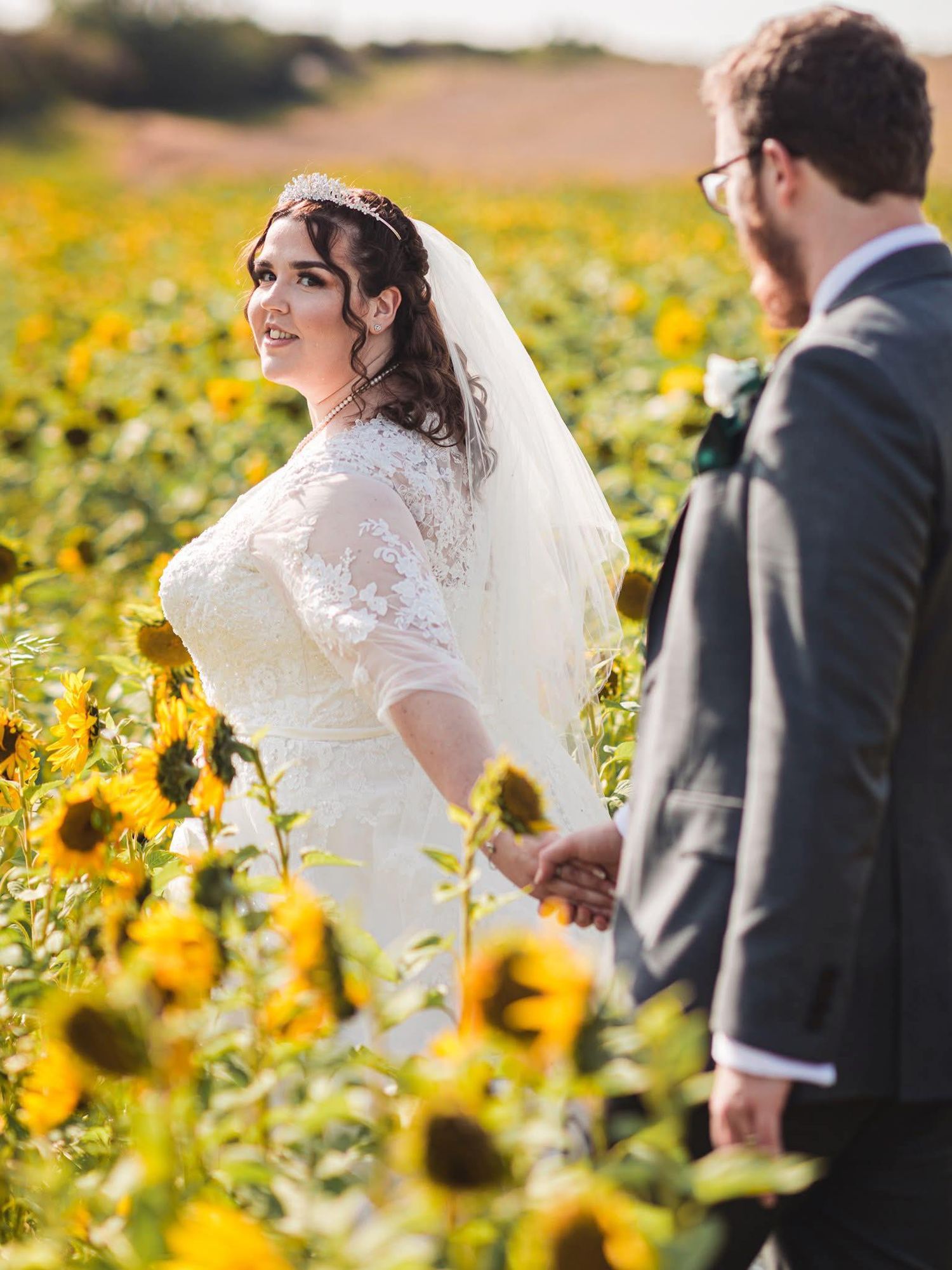 Wedding party poses in a vibrant sunflower field on a sunny day.