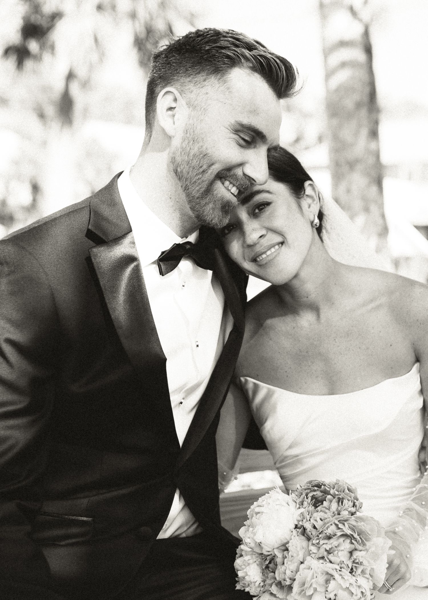 Black and white photo of smiling bride and groom embracing on their wedding day.