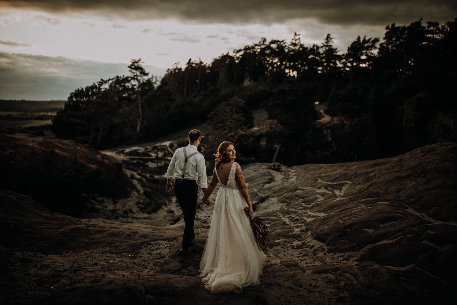 Braut steht auf einer Felsenlandschaft im Abendlicht, Wind im Kleid – emotionale Hochzeitsbilder in der Natur von Ann-Kathrin Bretschneider
