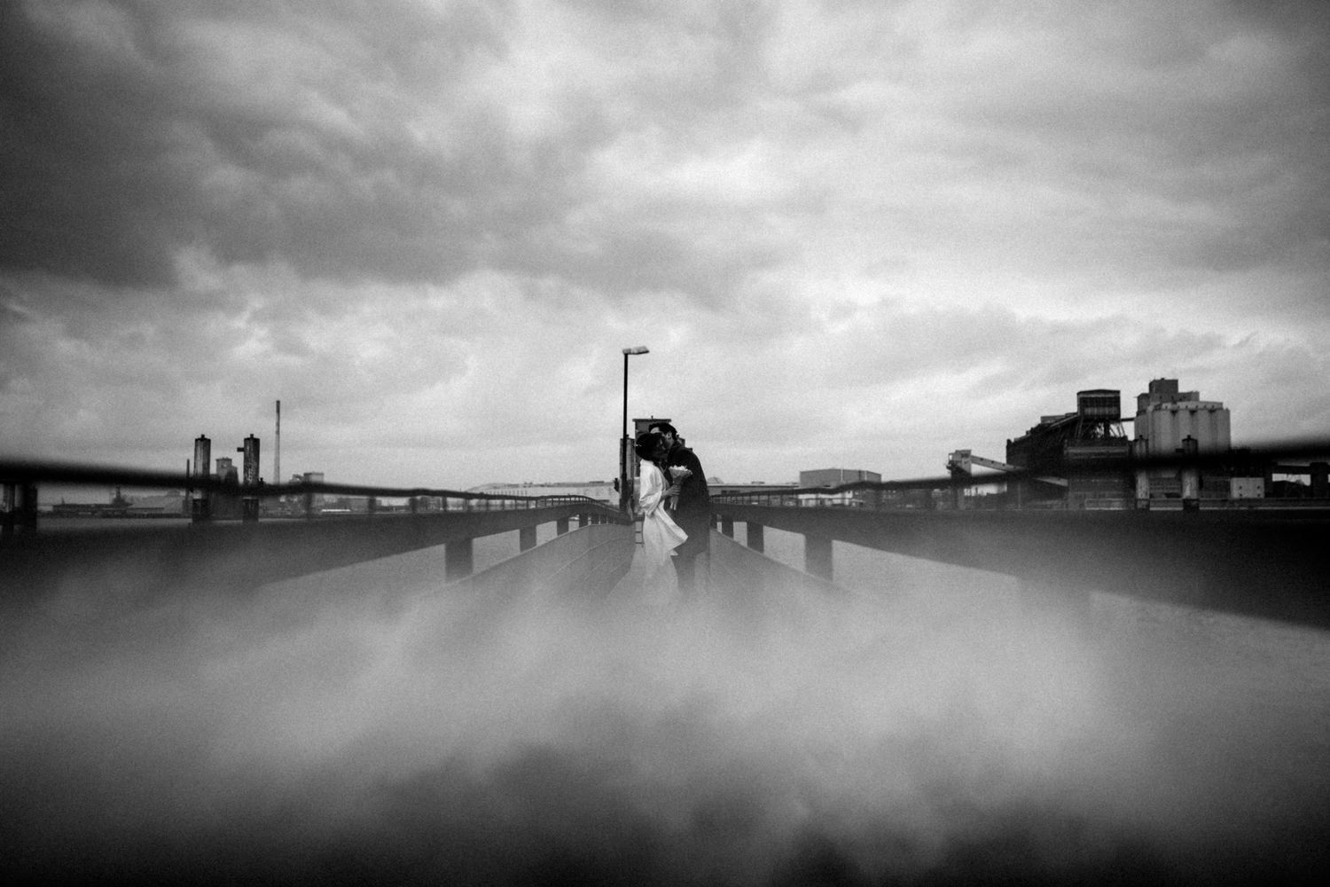 Brautpaar küsst sich auf einer Holzbrücke über der Weser – romantische Hochzeitsfotografie im Nebel von Ann-Kathrin Bretschneider.