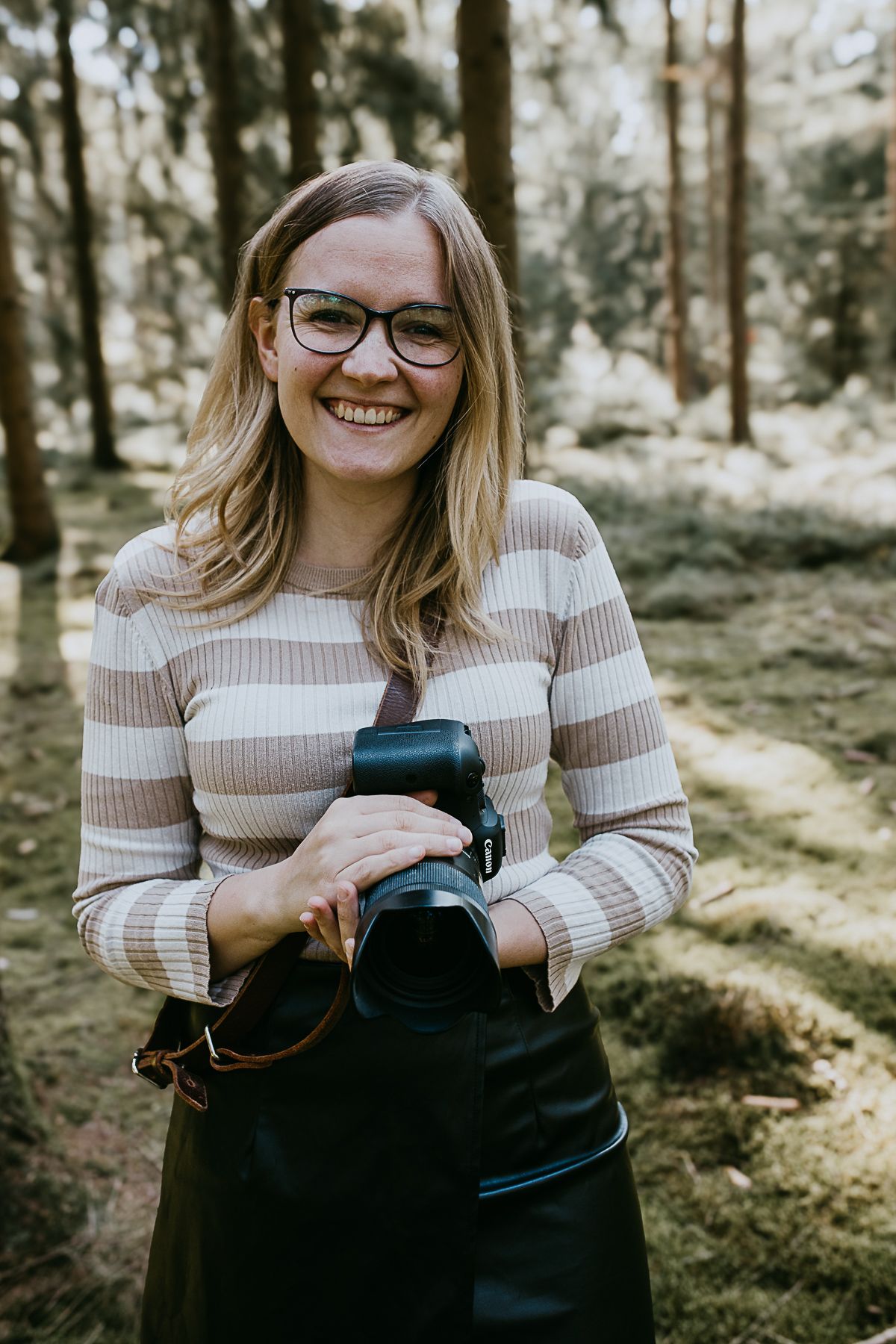 Fotografin hält Kamera und lächelt in die Kamera - natürliche und authentische Hochzeitsfotografie von Ann-Kathrin Bretschneider in ROW