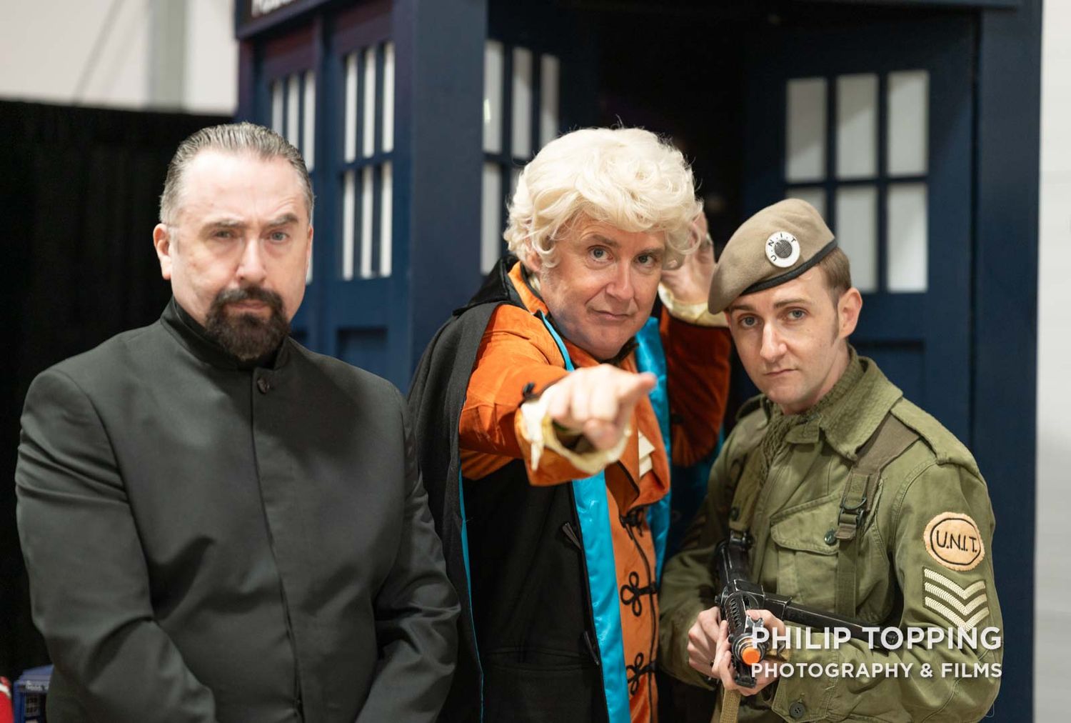 Doctor Who in the middle with The Master and an army soldier in front of the Tardis.