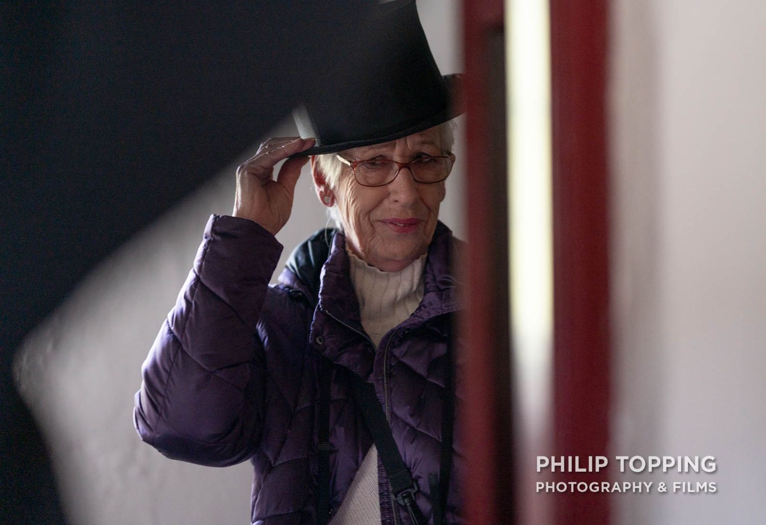Former chairperson Eileen McCausland tries on a hat, looking in the mirror.