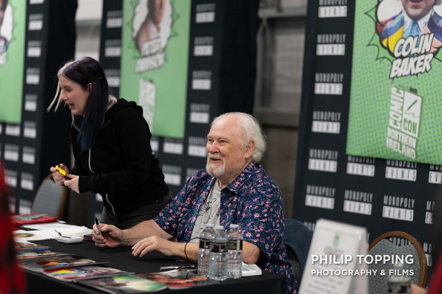 Colin Baker is sitting smiling.