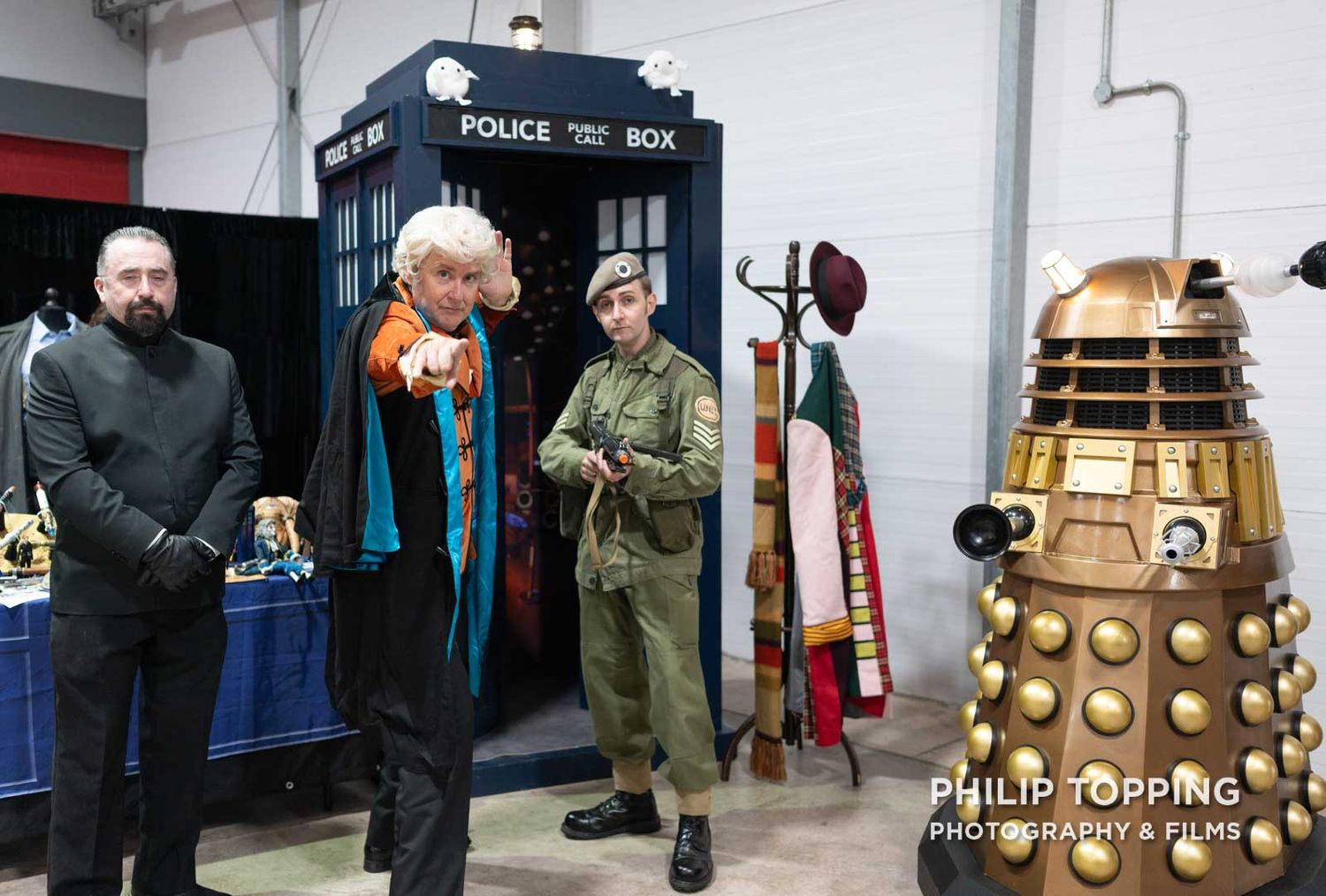 Doctor Who cosplayers beside a police box looking at the camera.