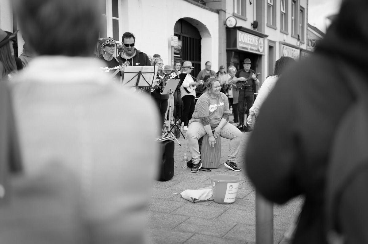 A female sitting down playing a drum stool..