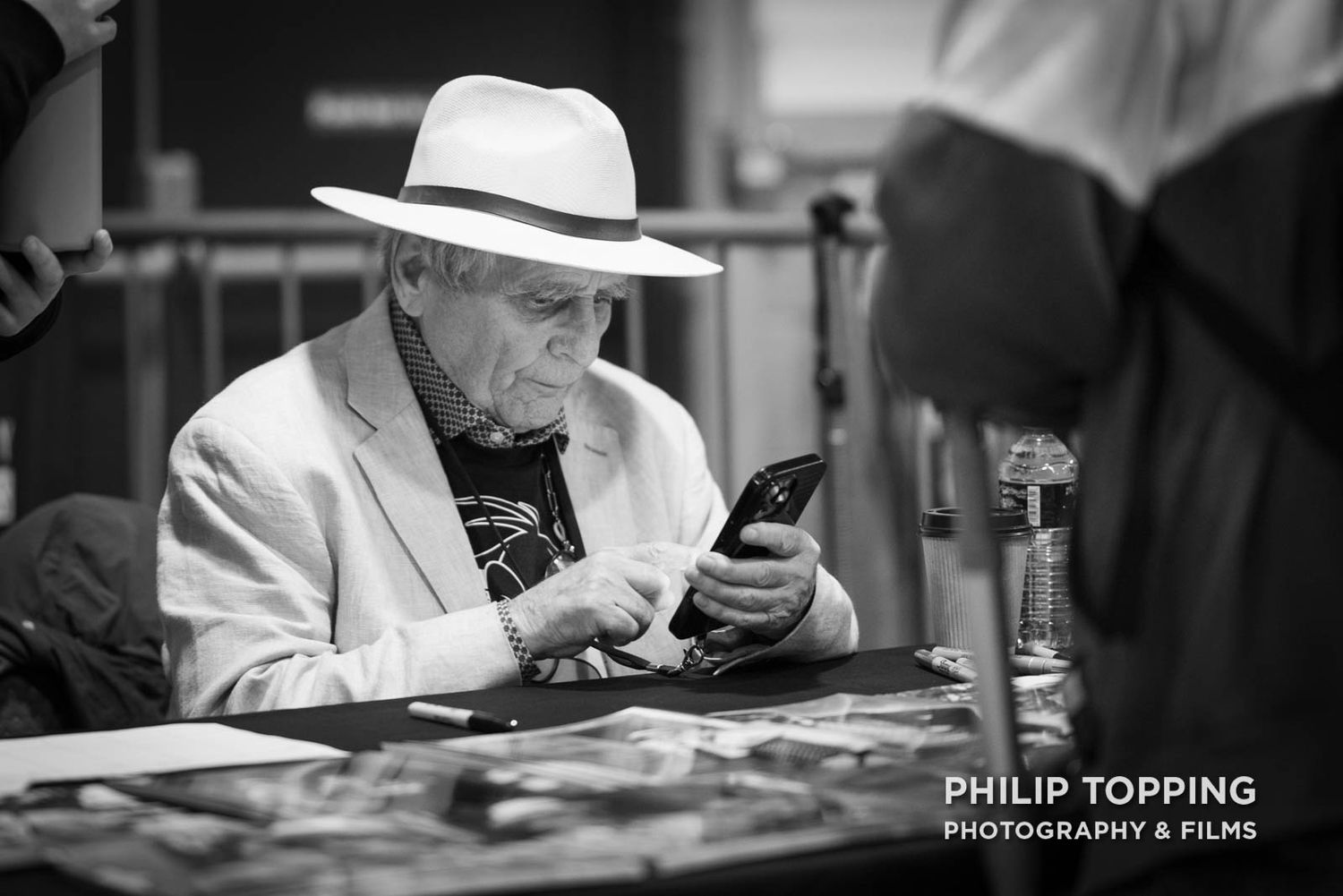 Mono image of a close-up of Sylvester McCoy on a smartphone.