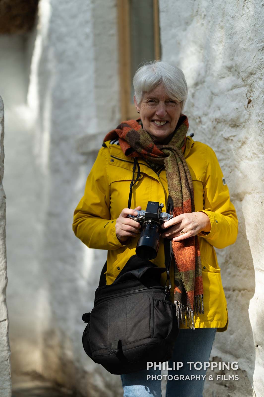 Club member at Dungannon and Cookstown Camera Club with a camera, smiling.